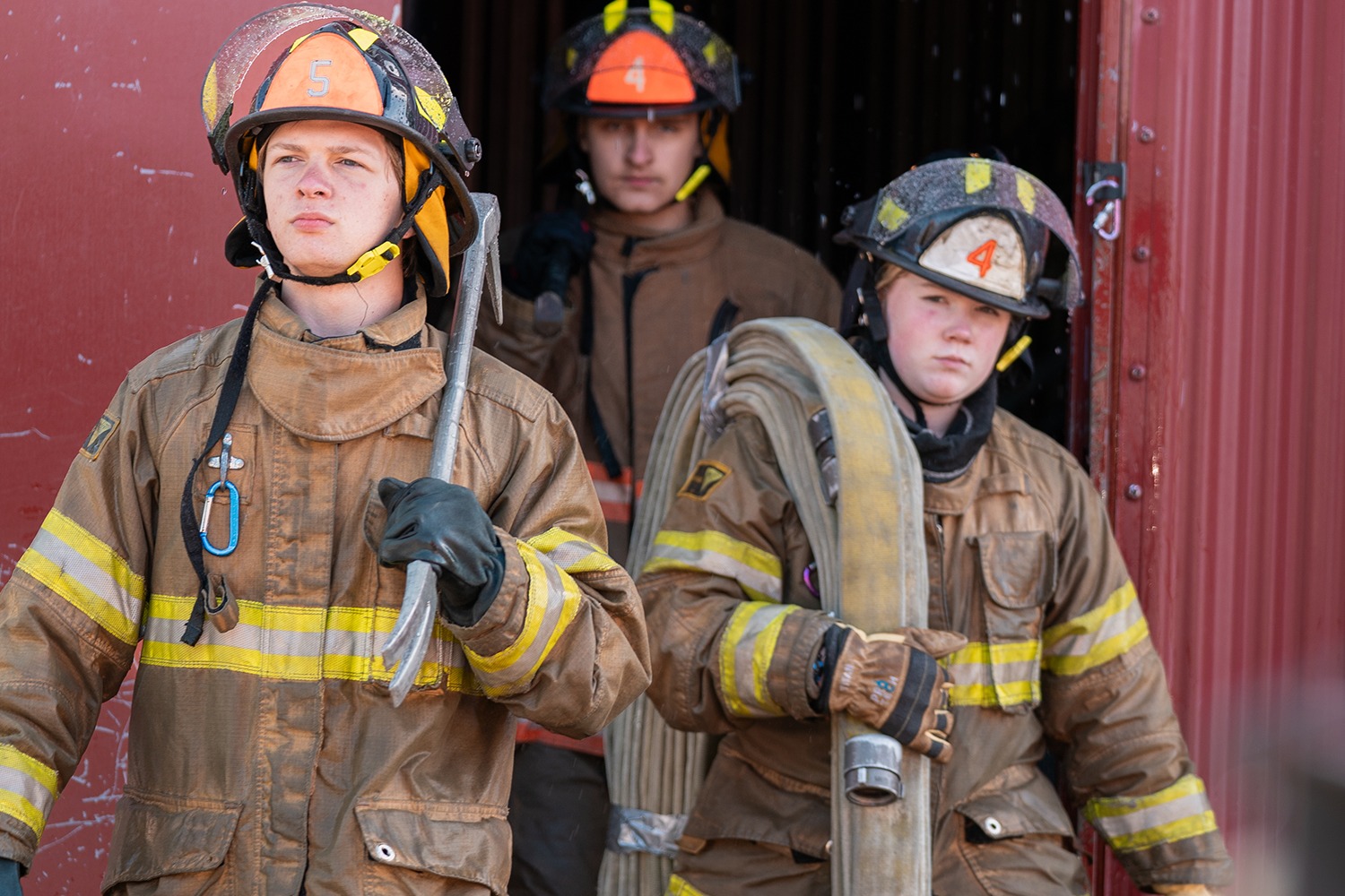 Student in turnouts holding fire hose