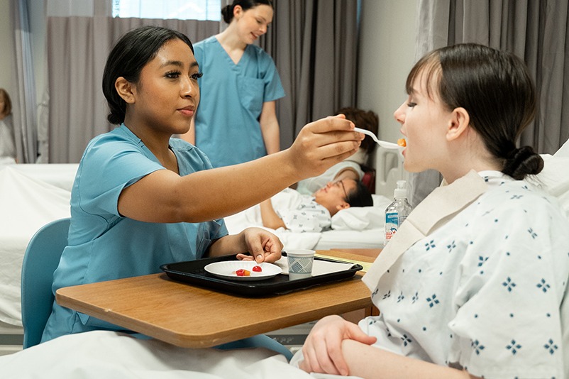 Students feeding a patient