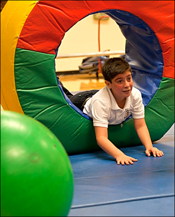 young child participating in physical education on mats and padding