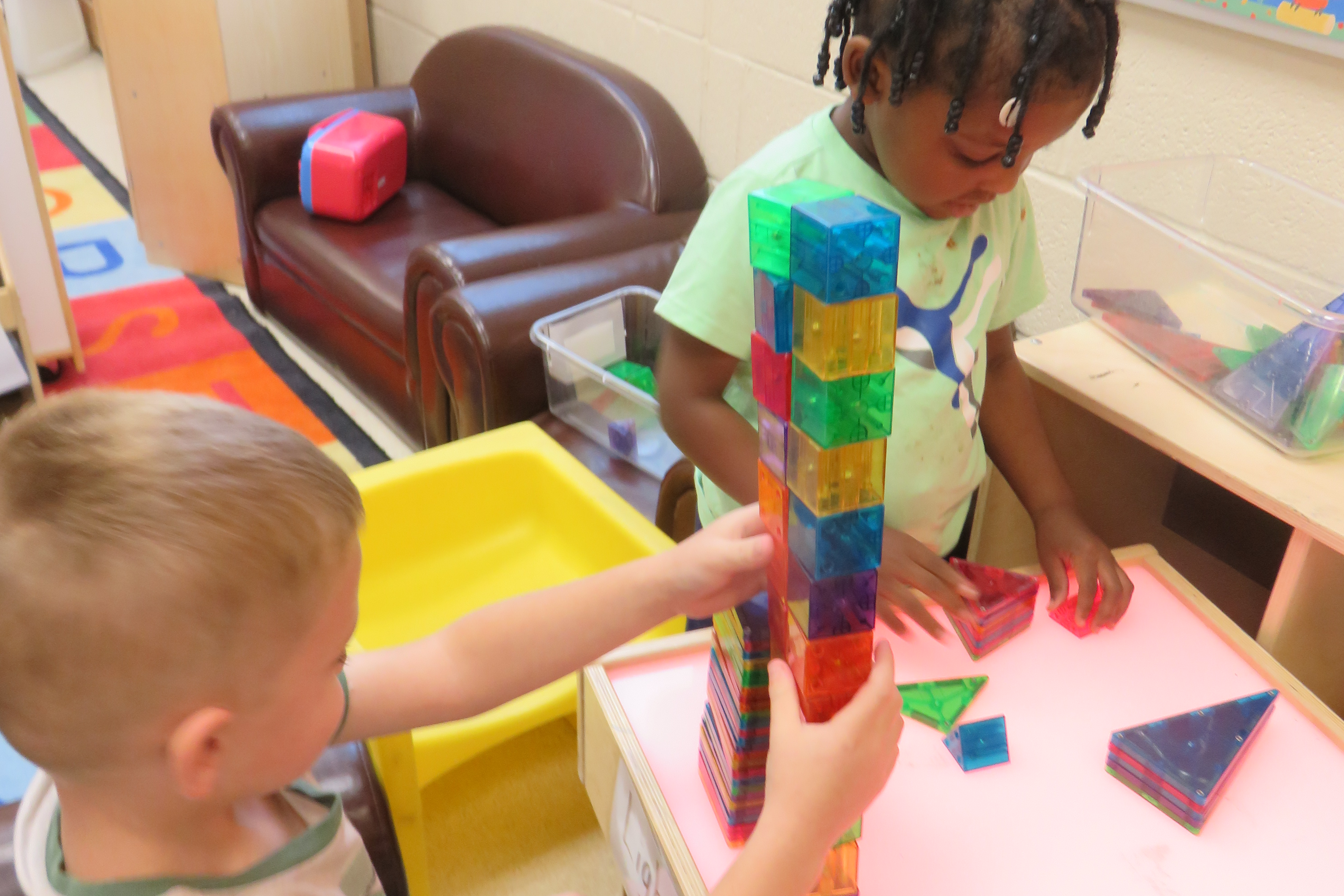 Preschool scholars playing with magnetic blocks.