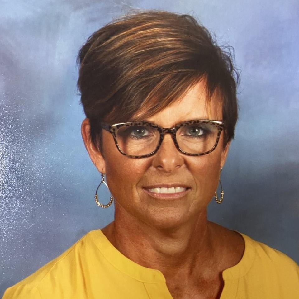 Mrs. Petty in a yellow shirt with a blue background