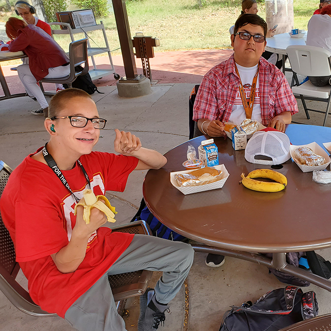 Students eating lunch at an outdoor table.