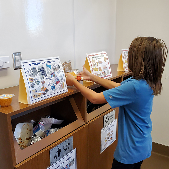 Student using recyling station in cafeteria.