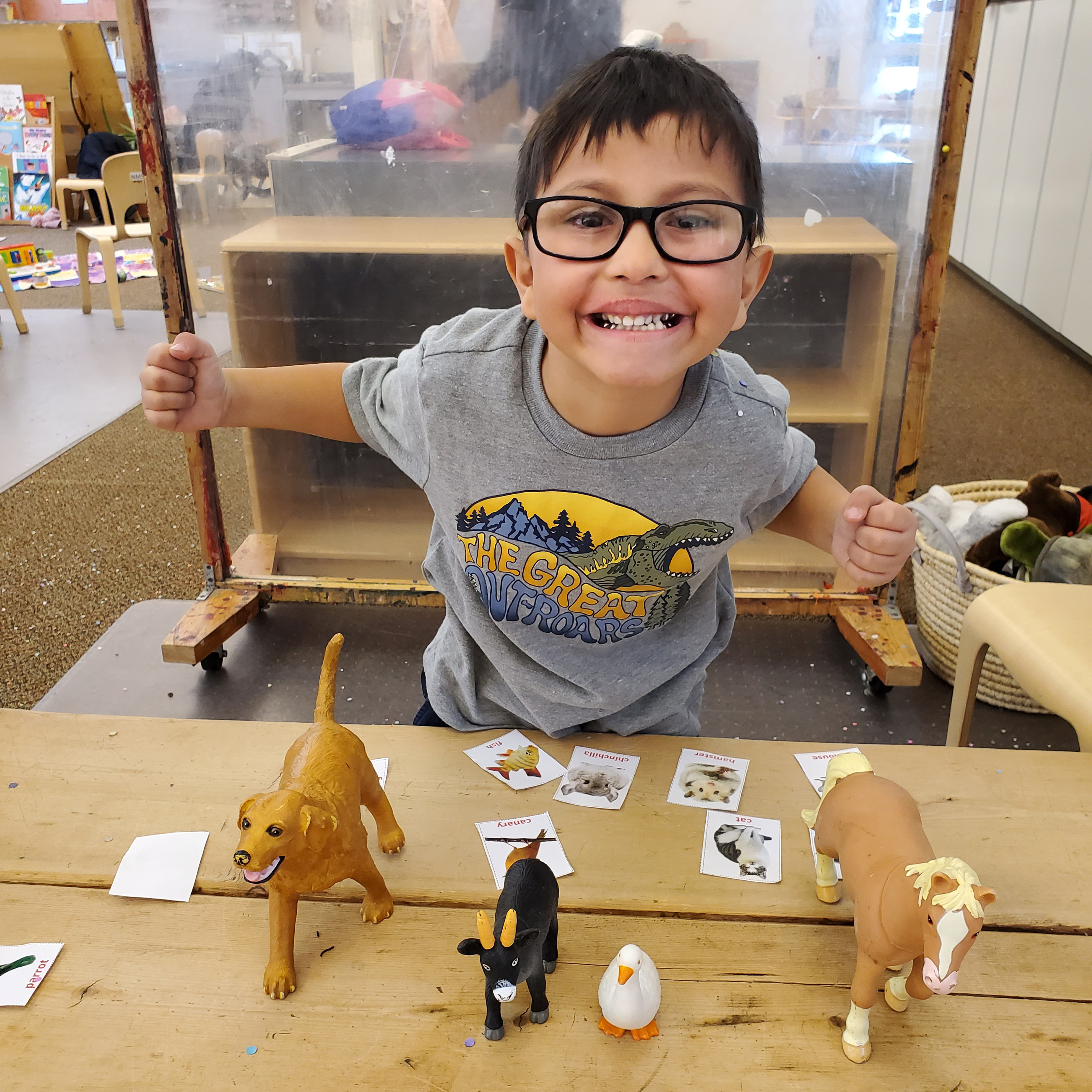 Prek Student learning about animals with toy dog, goat, duck, & horse.