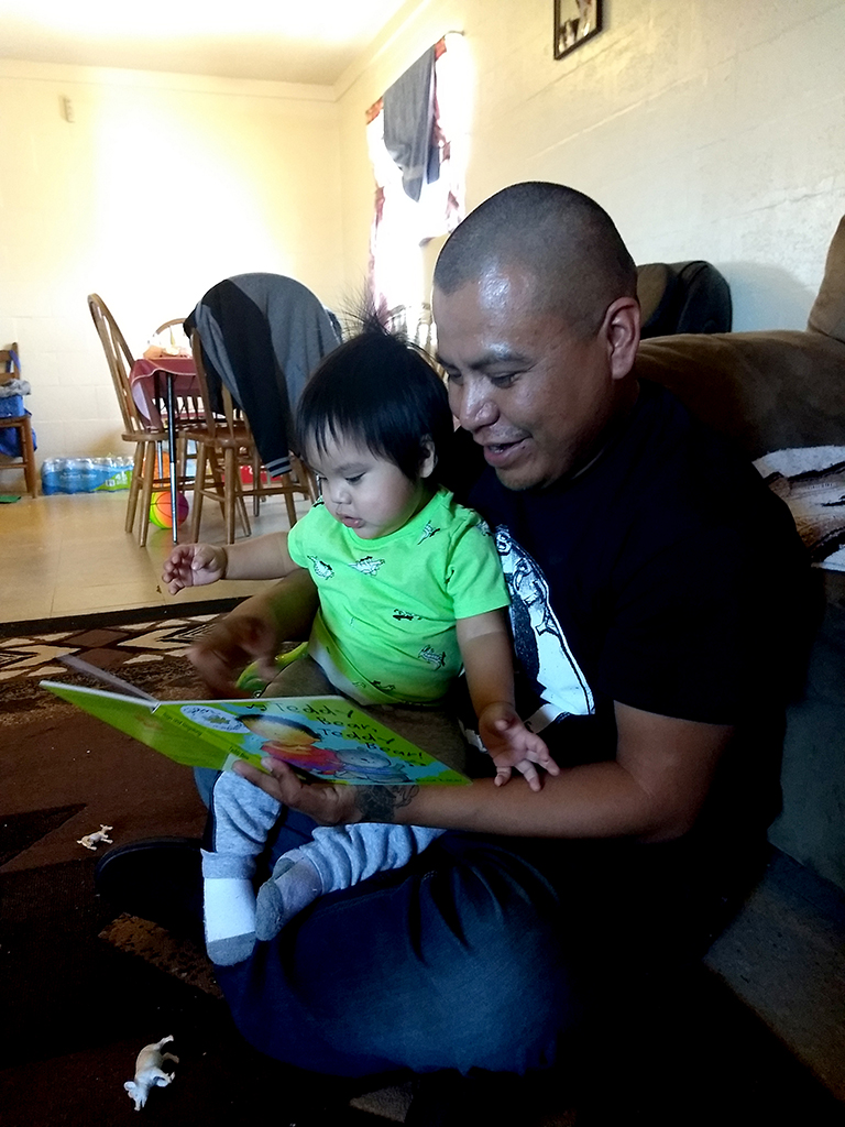 Father reading to babysitting on his lap  during EIDS home visit