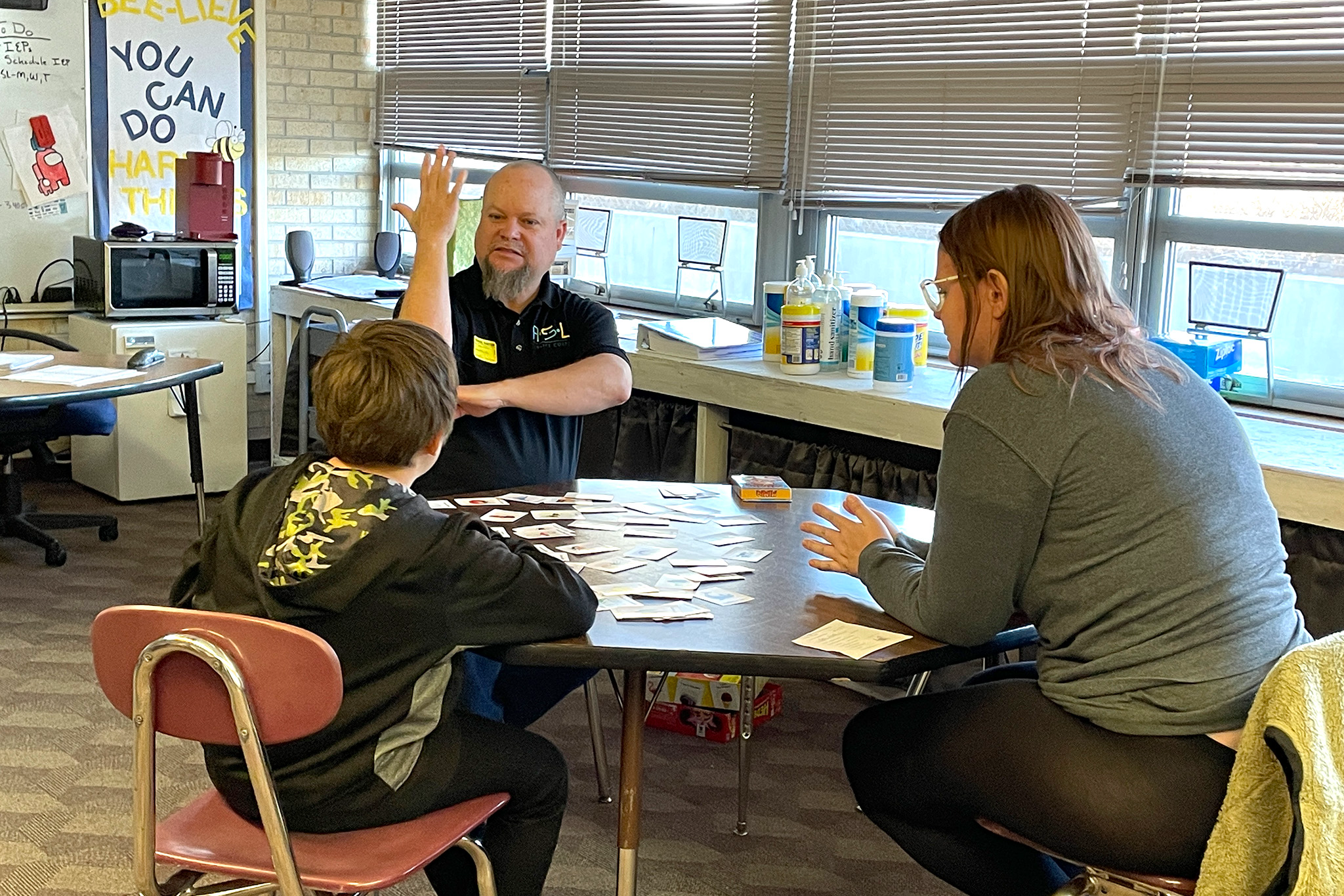 Deaf Tutor signing "tree" while working with a student and teacher in the public schools