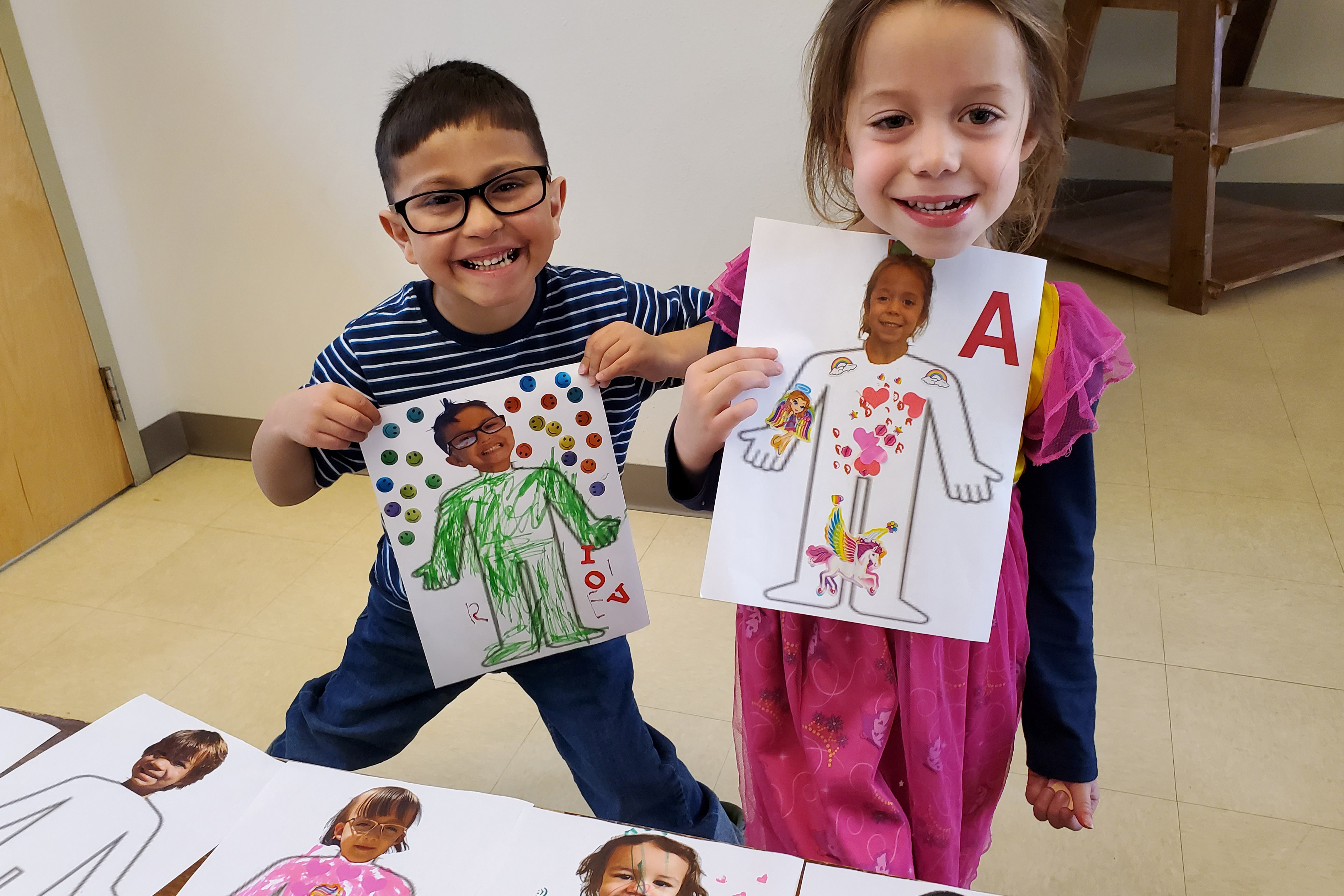 Two Preschool student showing their art pieces.