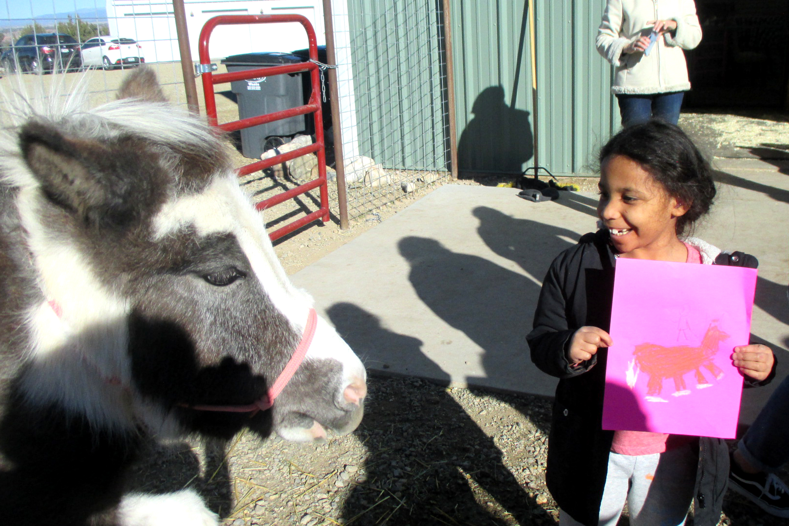 Elementary student with mini horse and her drawing of the horse.