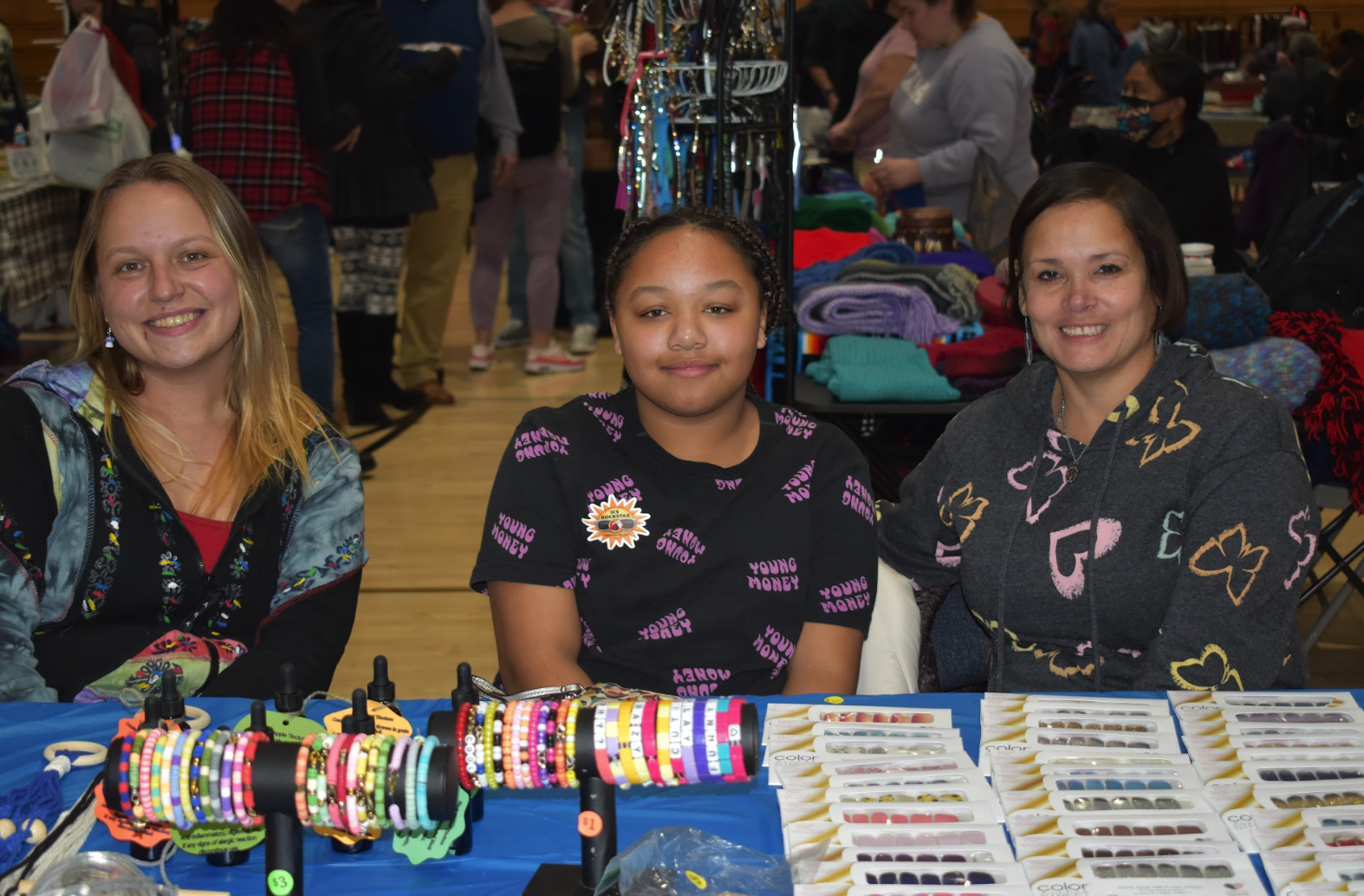 Two ICS teachers and a student sitting at their table selling jewelry.