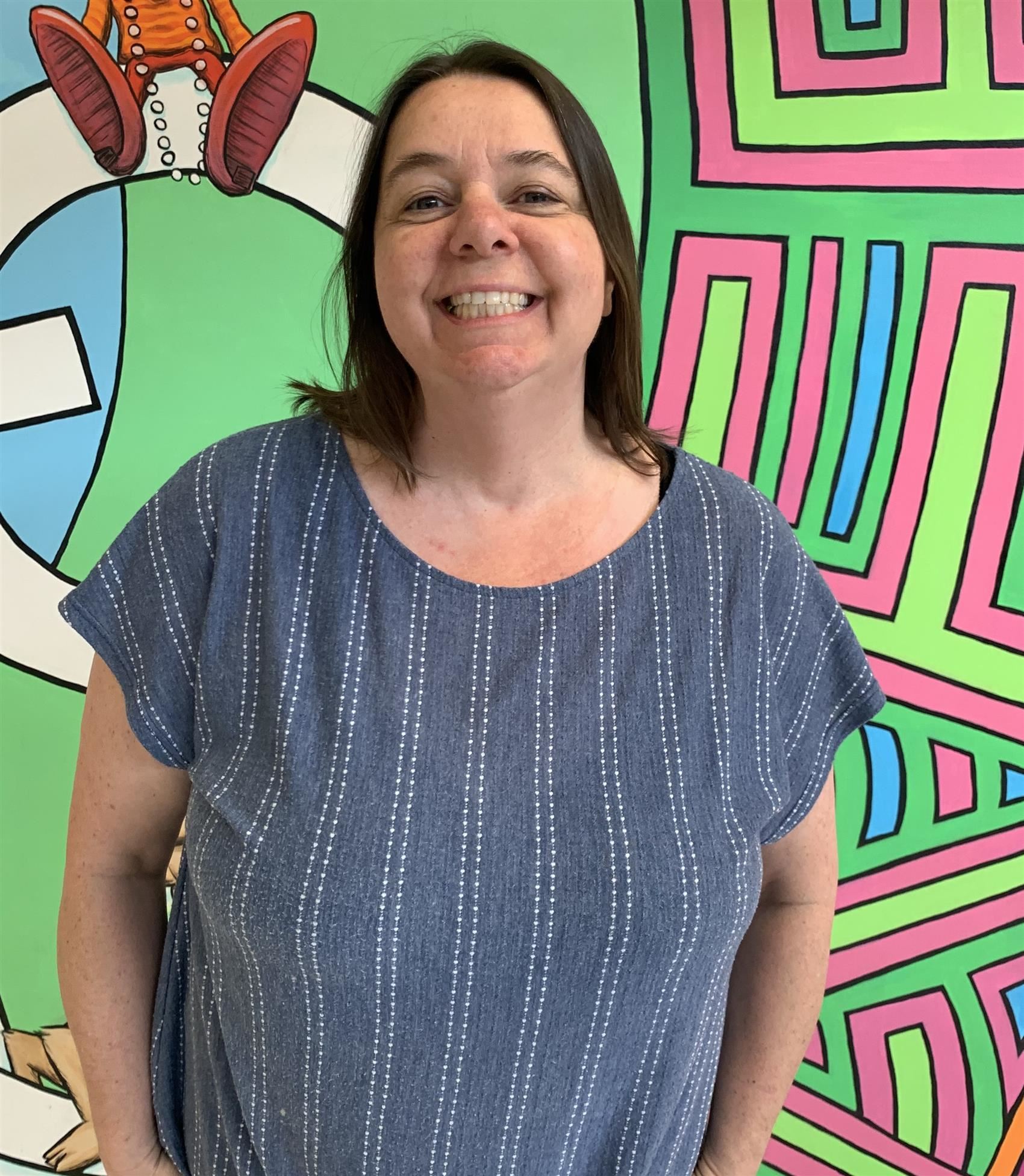 Mrs. Glass smiling in front of a brightly patterned wall