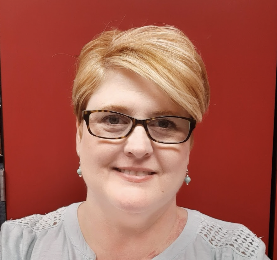 Mary Lasater, a woman with glasses and short hair, smiling