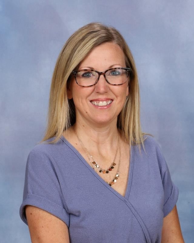 Woman wearing glasses with a blue blouse in front of gray background