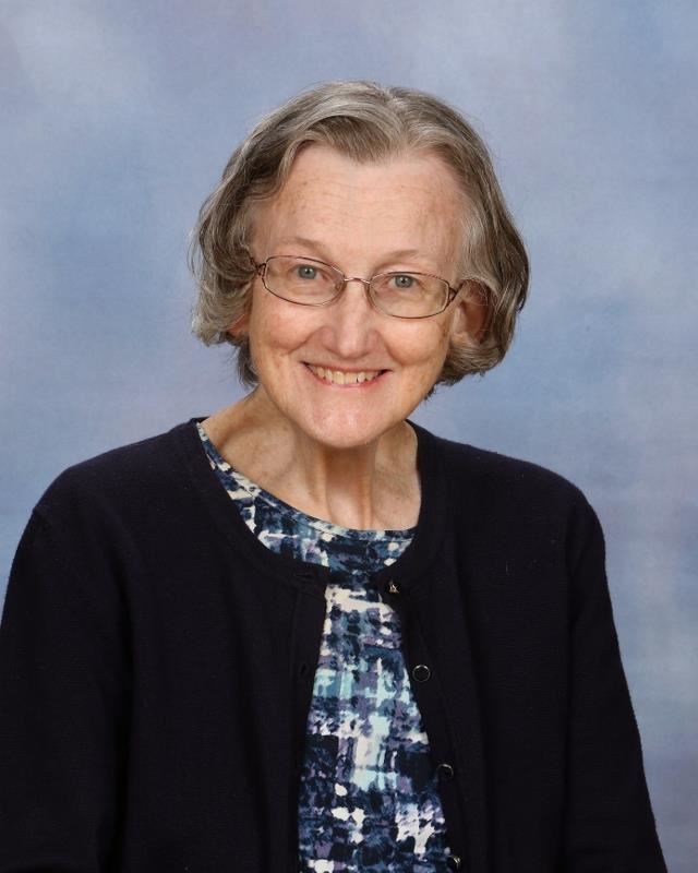 Smiling woman wearing black blazer in front of gray background