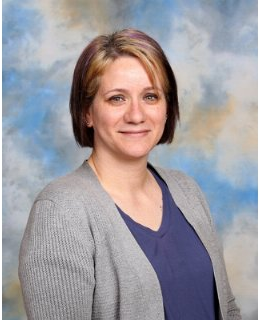 Woman wearing dark blouse in front of gray background