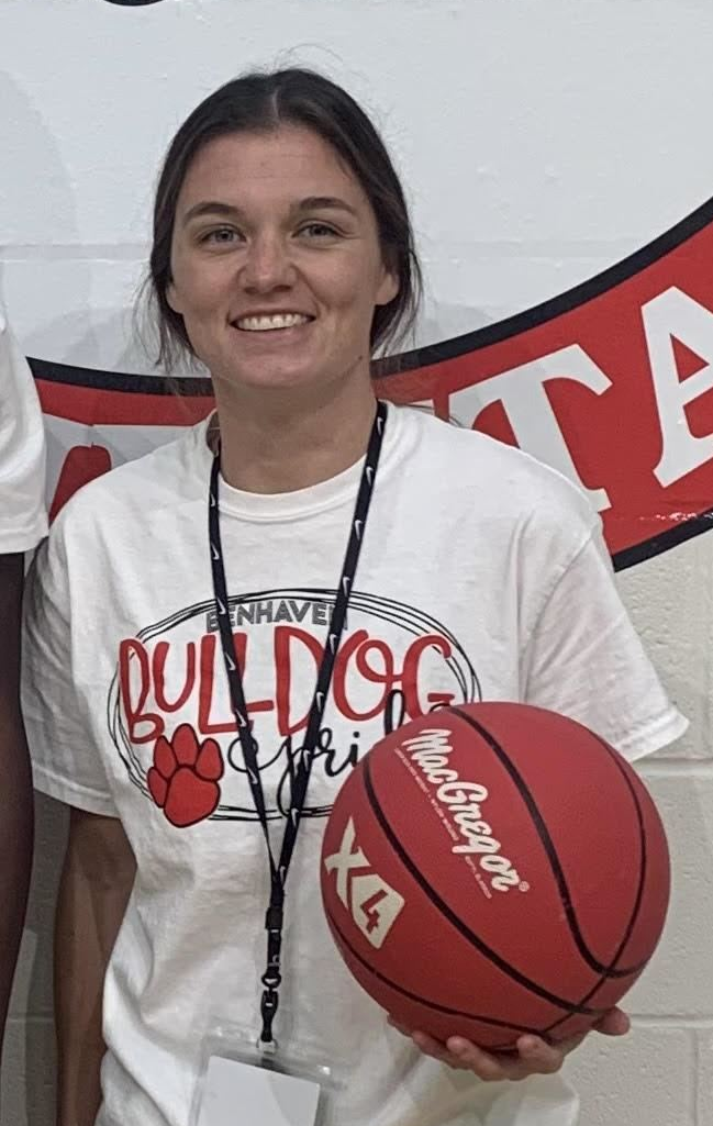 Woman wearing white shirt and black shorts holding a basketball
