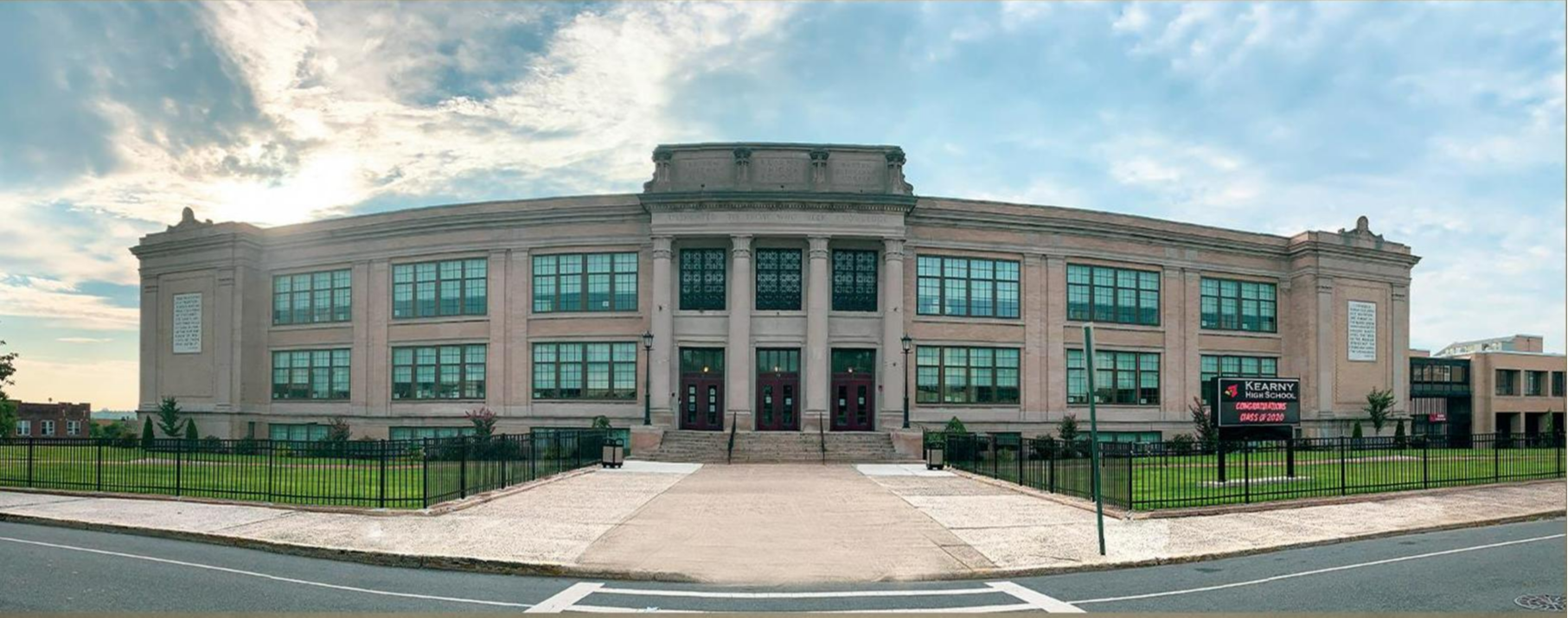  Kearny High School building - grey brick with large columns, brown windows and a green lawn