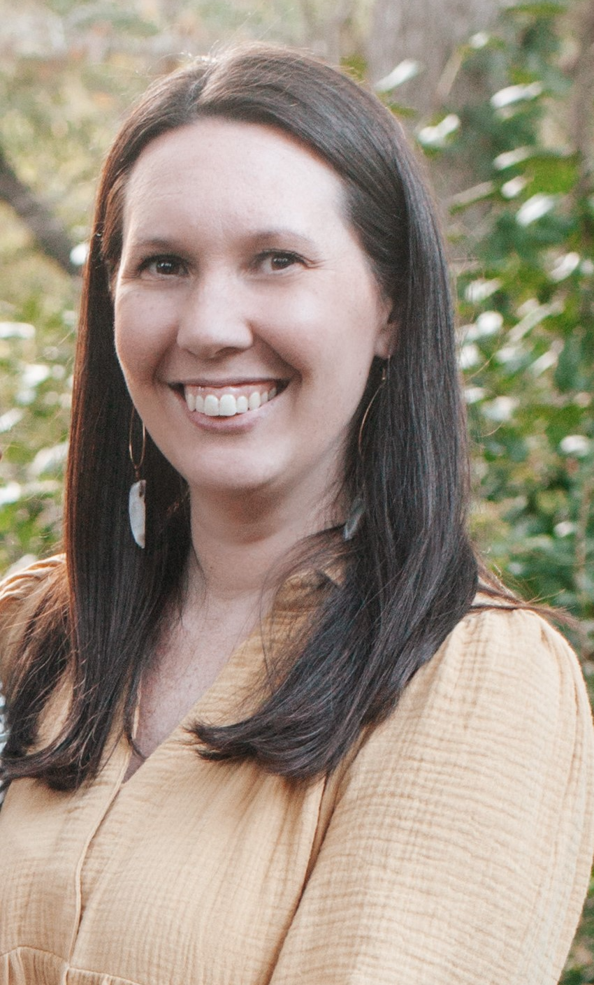 Dark haired woman smiling wearing plaid