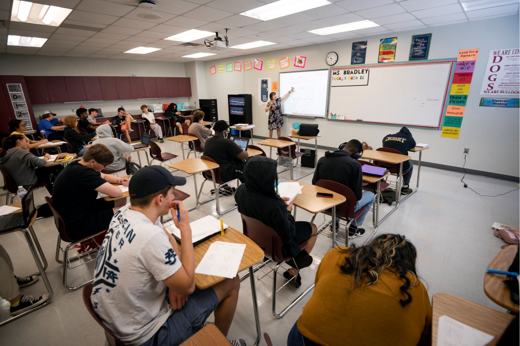 Teacher points to whiteboard in high school class 