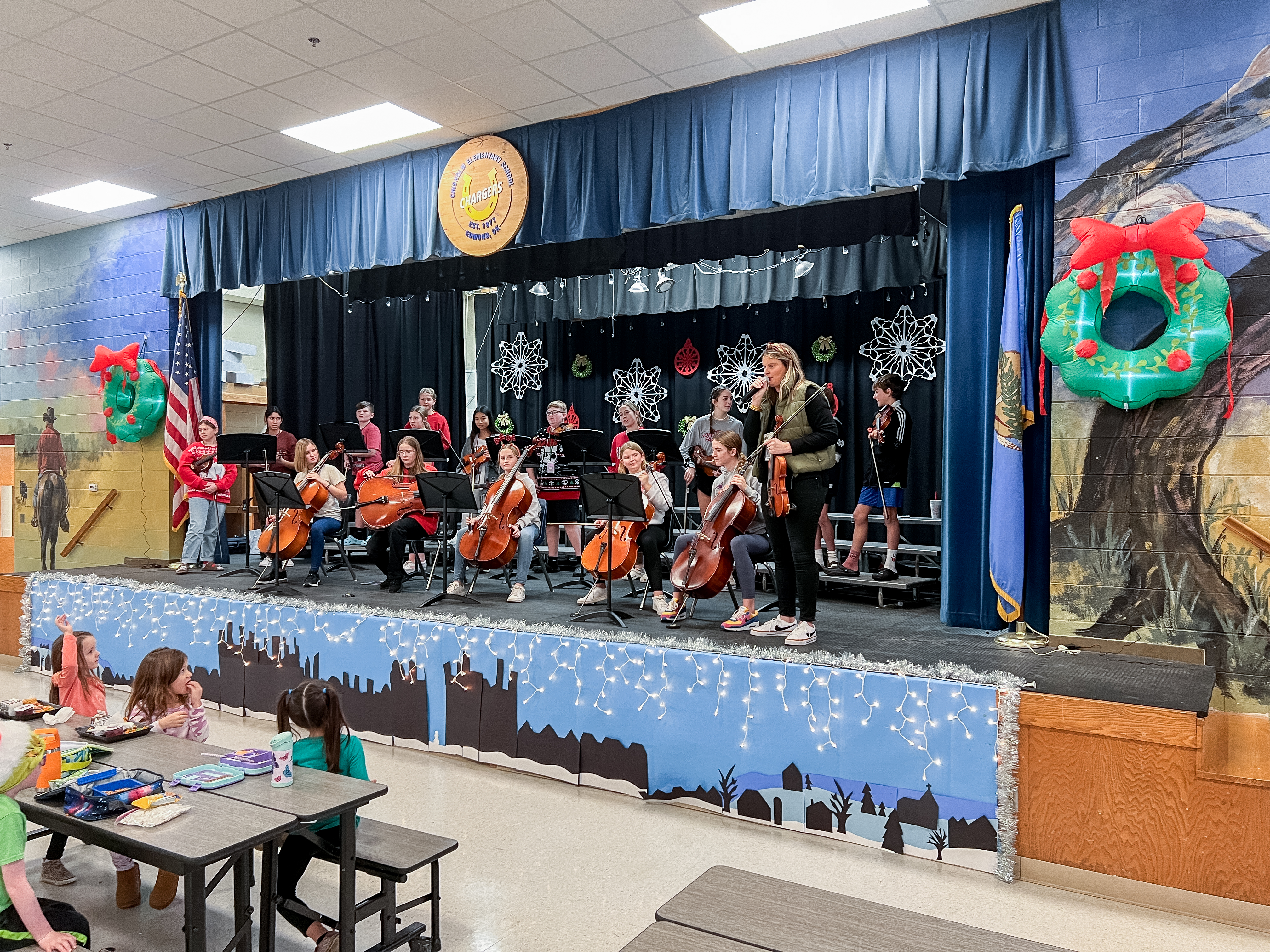 group of middle school orchestra students performing for elementary students