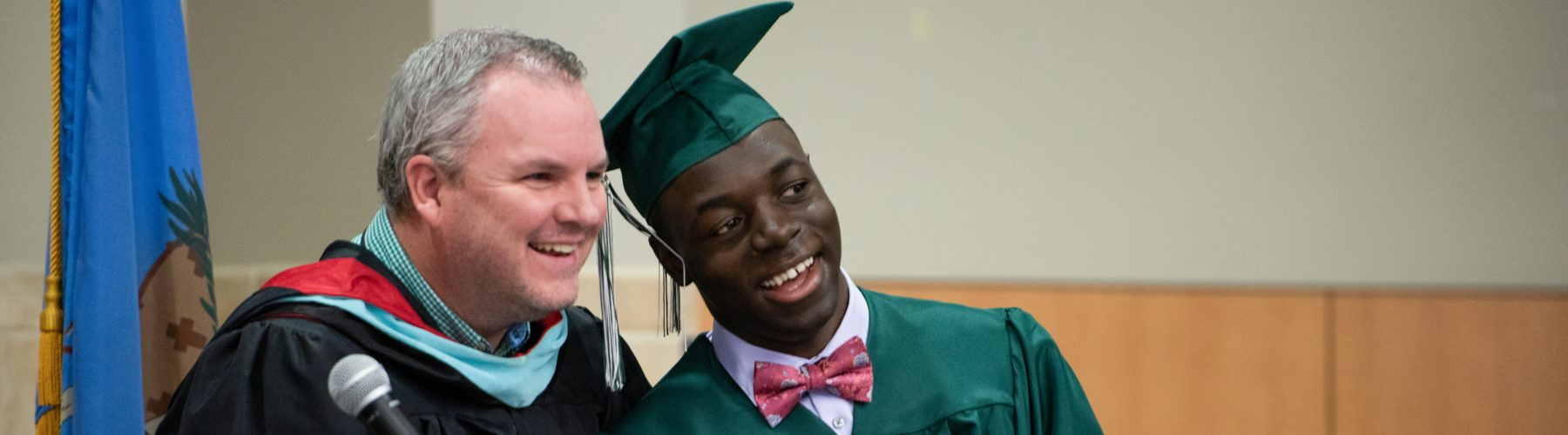Mission, Vision, Core Values a white teacher with an african american student in graduation clothing