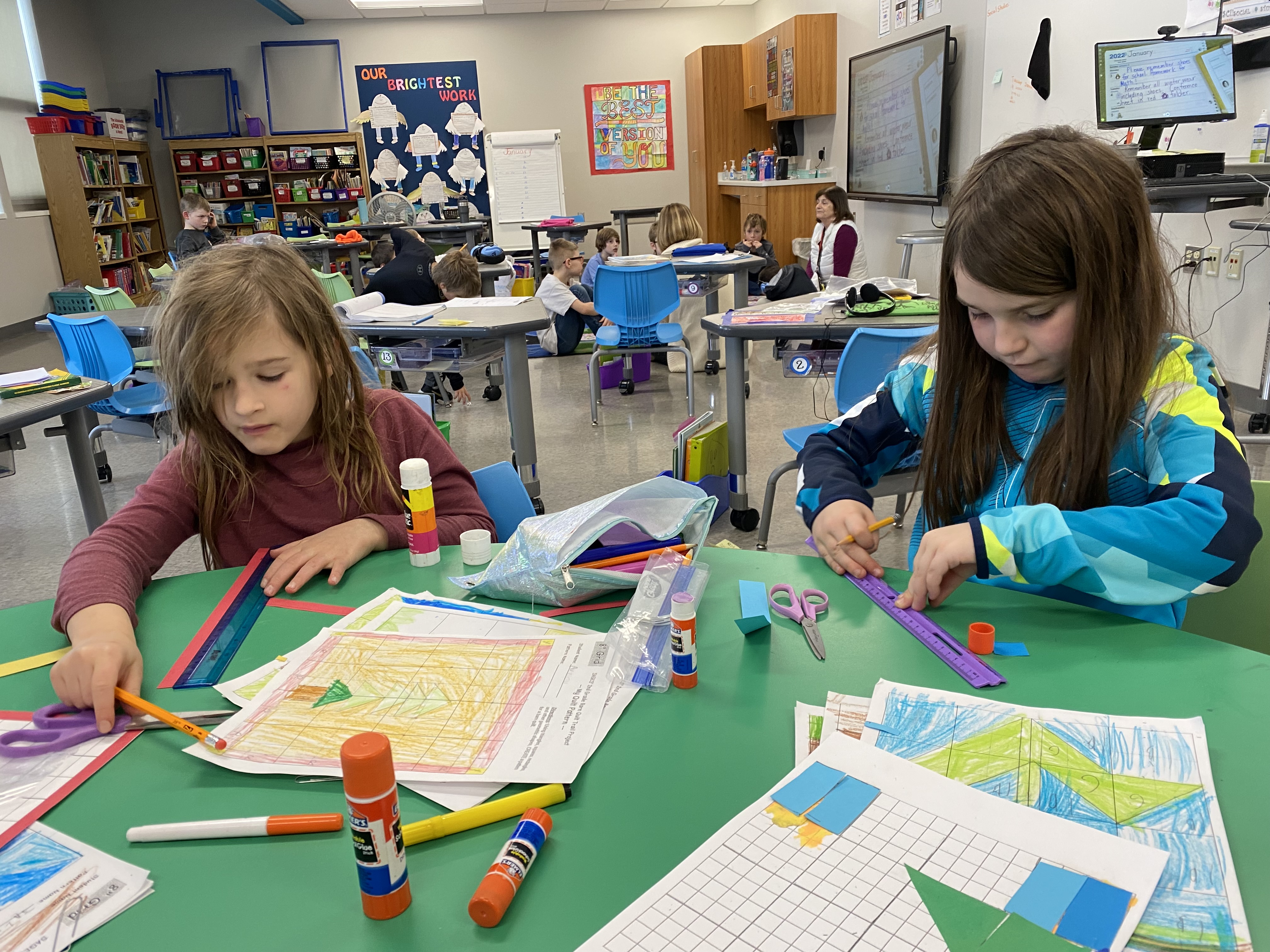 Two of SAGES second graders work to measure construction paper pieces for their paper barn quilts.