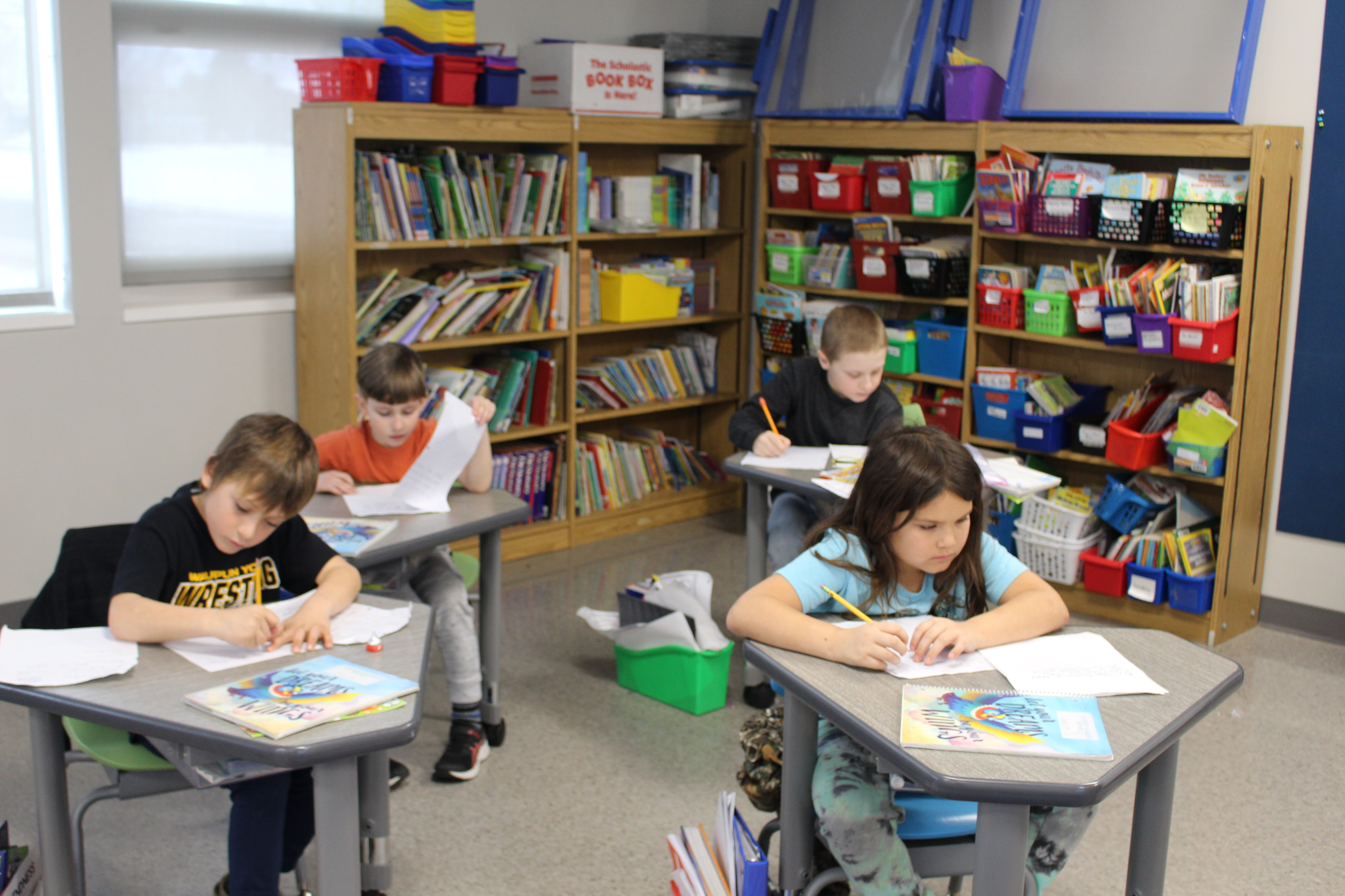 Four of SAGES 2nd Graders work on writing persuasive pieces about their paper barn quilt pattern.