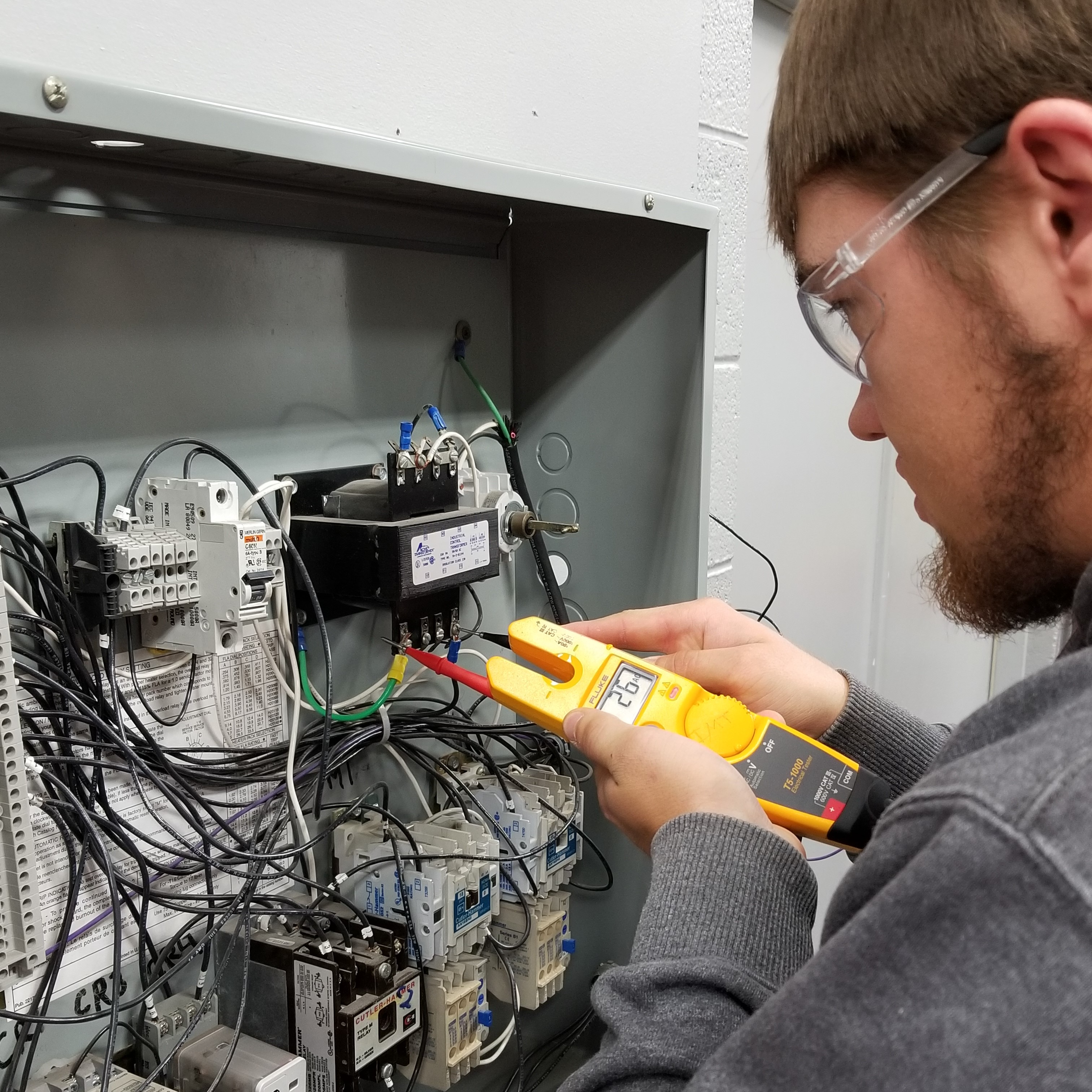 student works on checking electrical in a breaker box