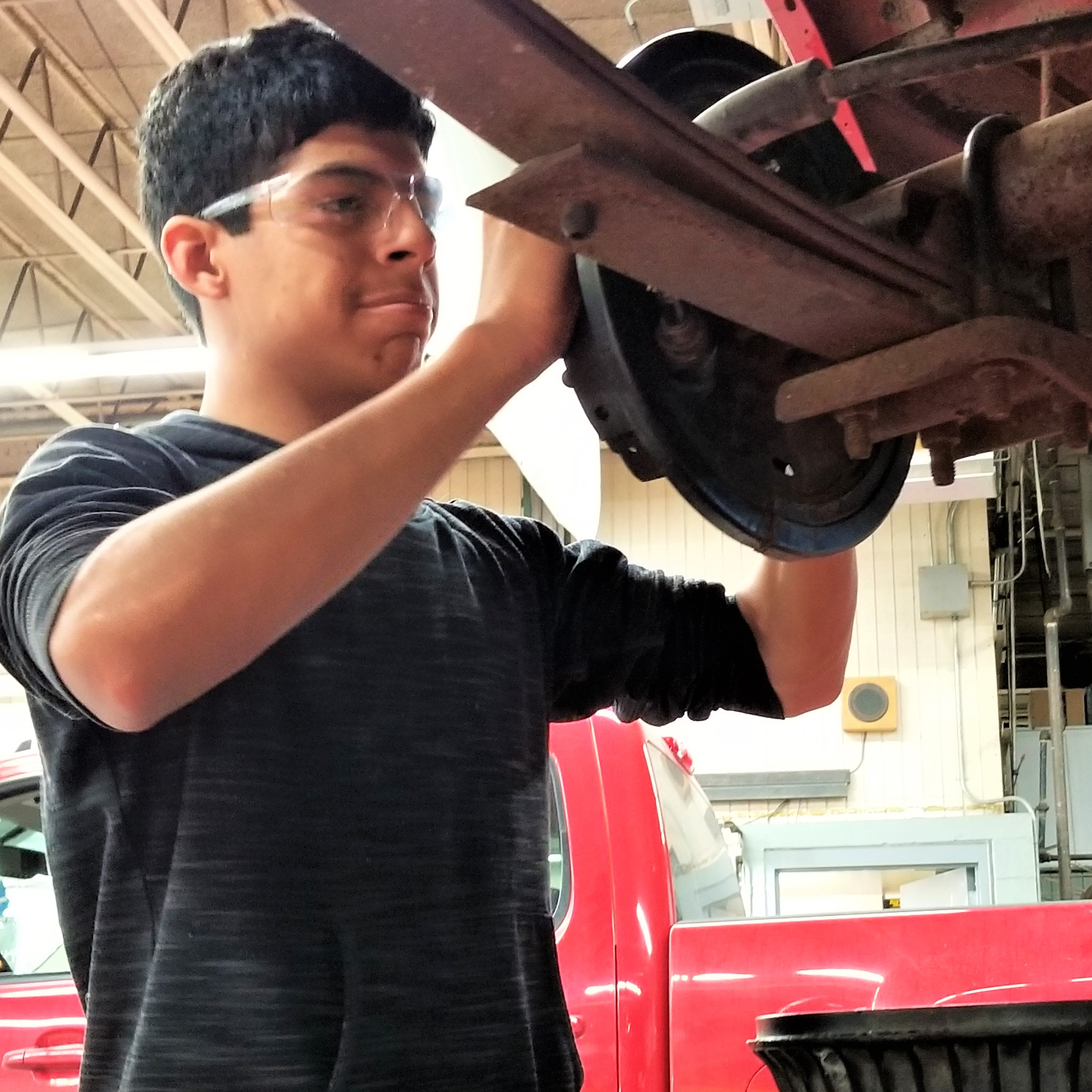 student works on vehicles brakes