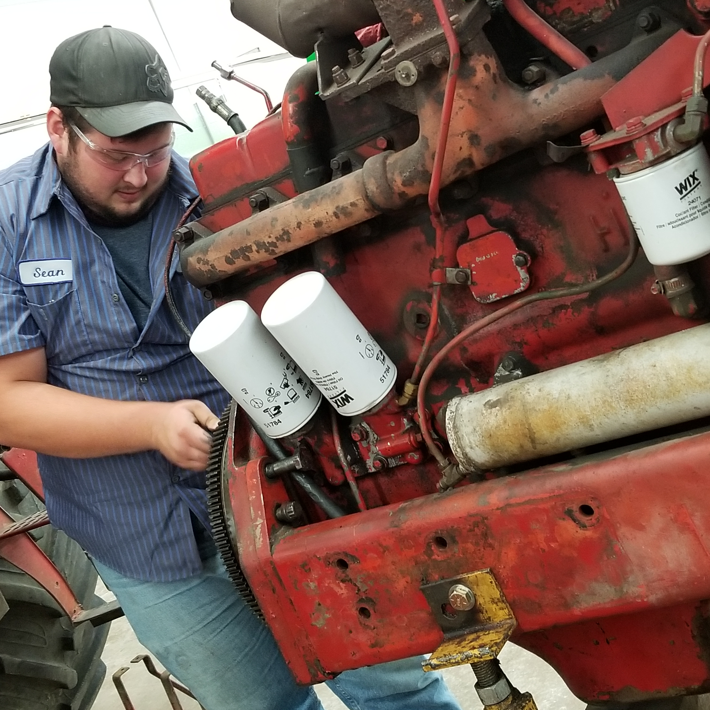 student works on rebuilding a diesel engine on a tractor