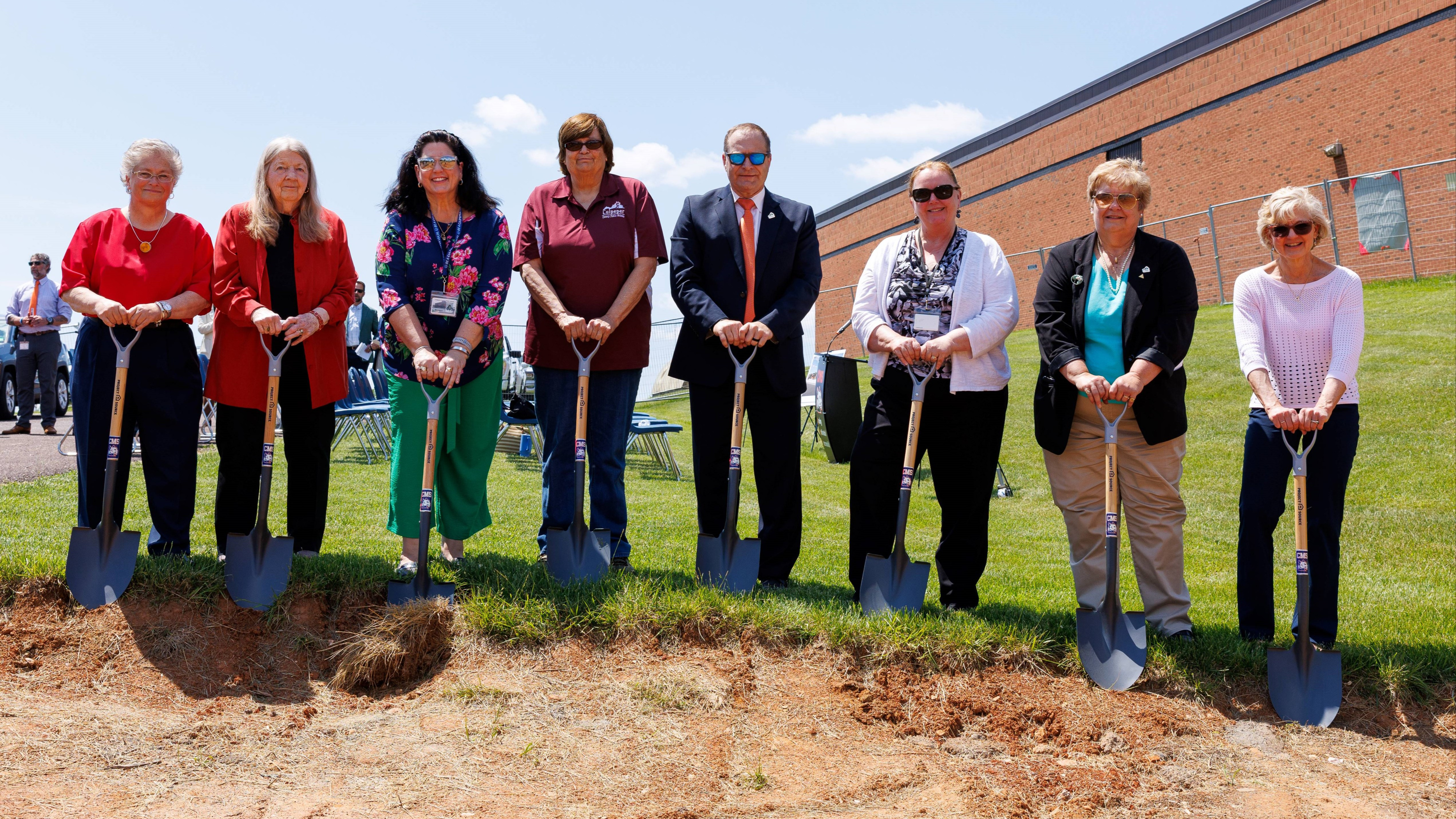 school board members and superintendent holding shovels by dirt pile at CMS groundbreaking ceremony