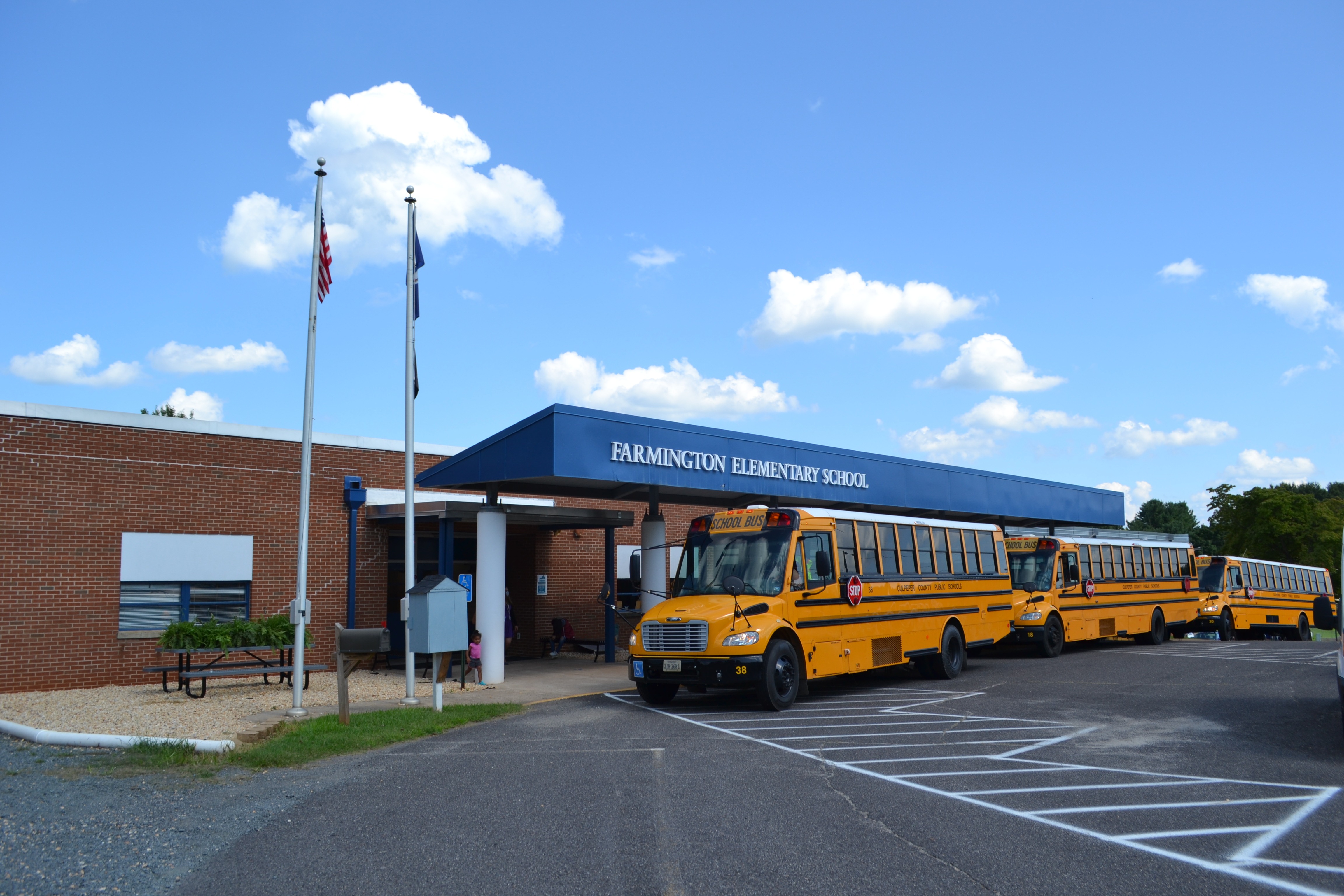 Three school buses sit in front of Farmington Elementary