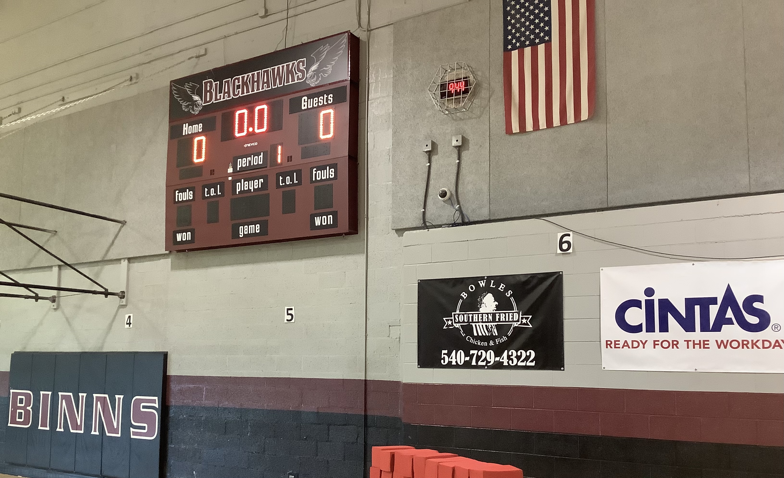 A picture of the two sponsor banners, Cintas and Bowles Southern Fried Chicken and Fish, in our gym by the scoreboard