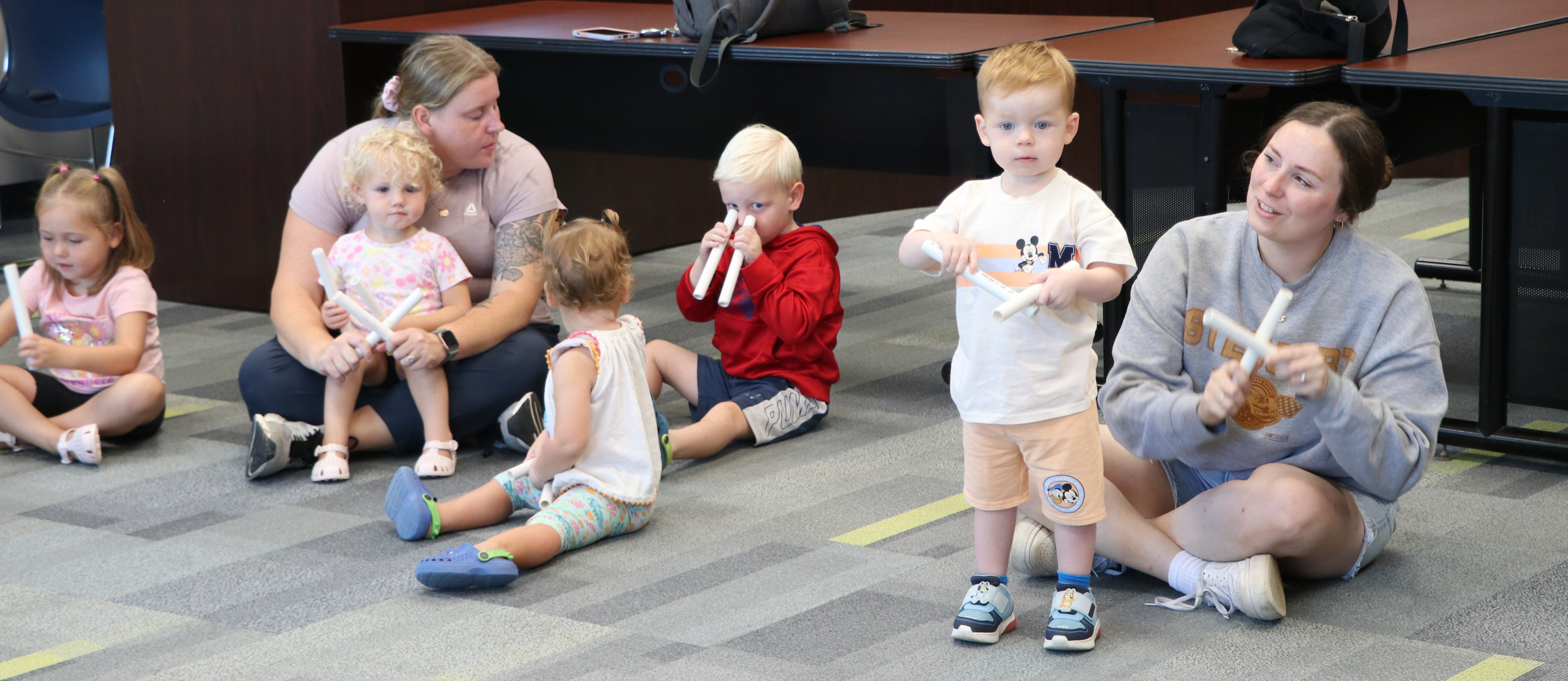 Parents as teachers moms and children tap sticks to the beat of the song
