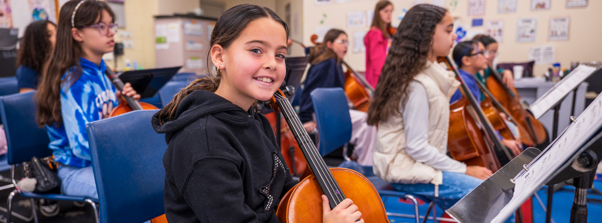 A student smiles while holding a cello