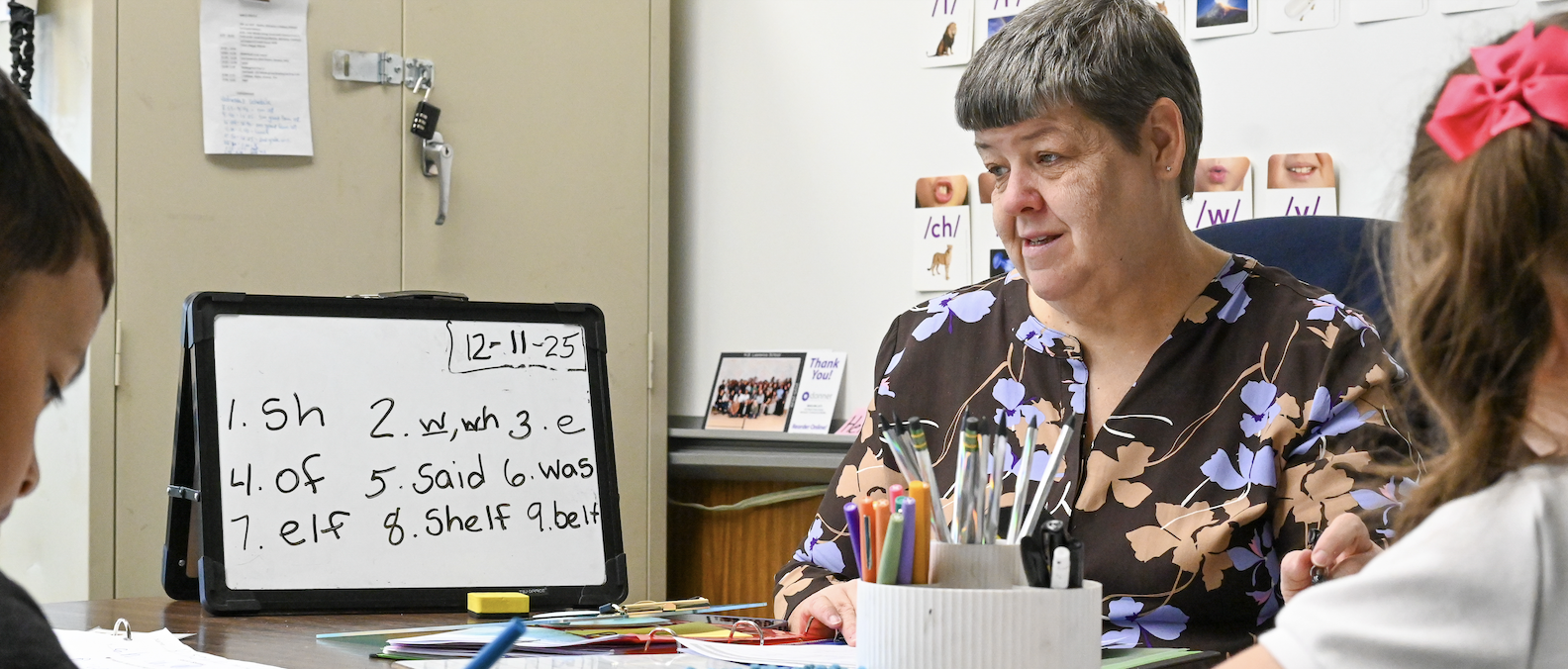 A staff member works on phonics with students