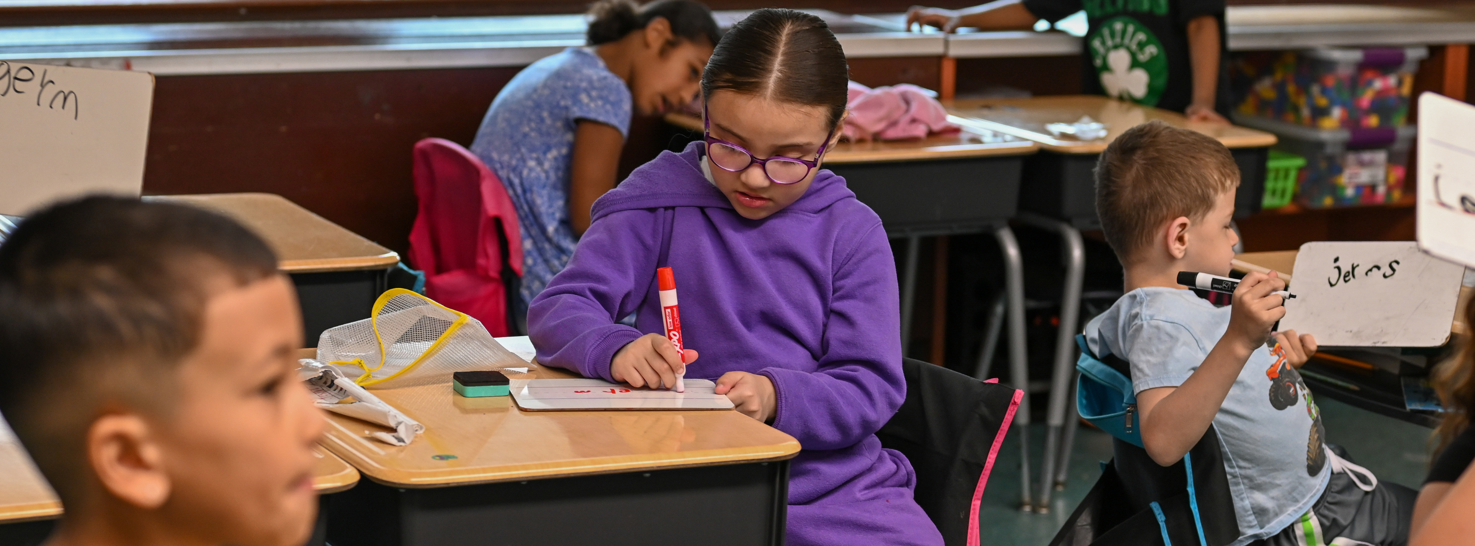 student sitting at table working on a whiteboard in class