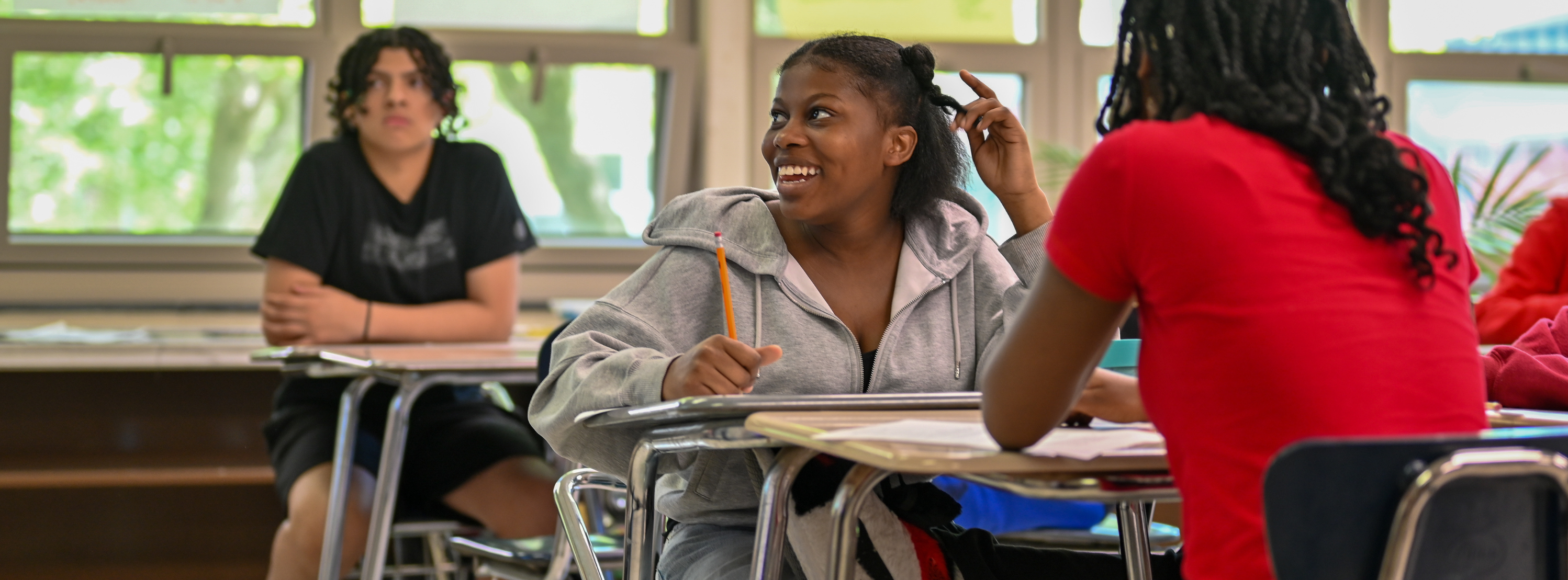 student smiling in class while sitting at her desk