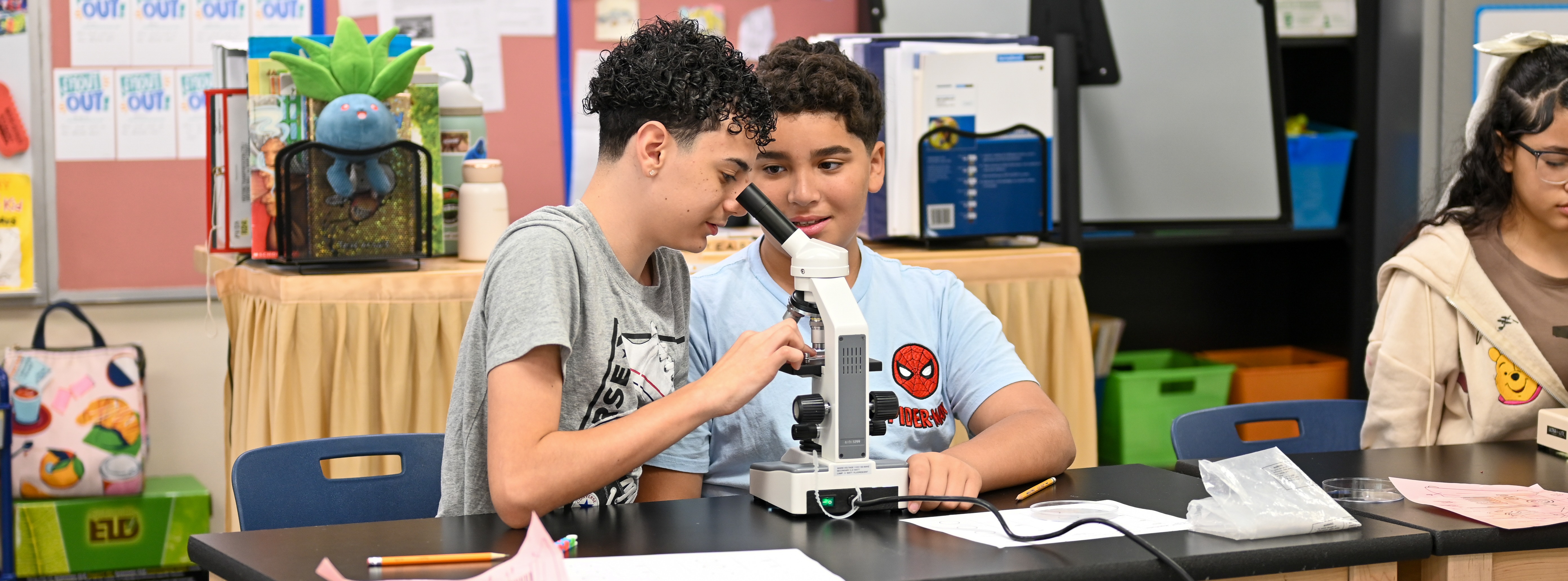 two students working with a microscope in science class
