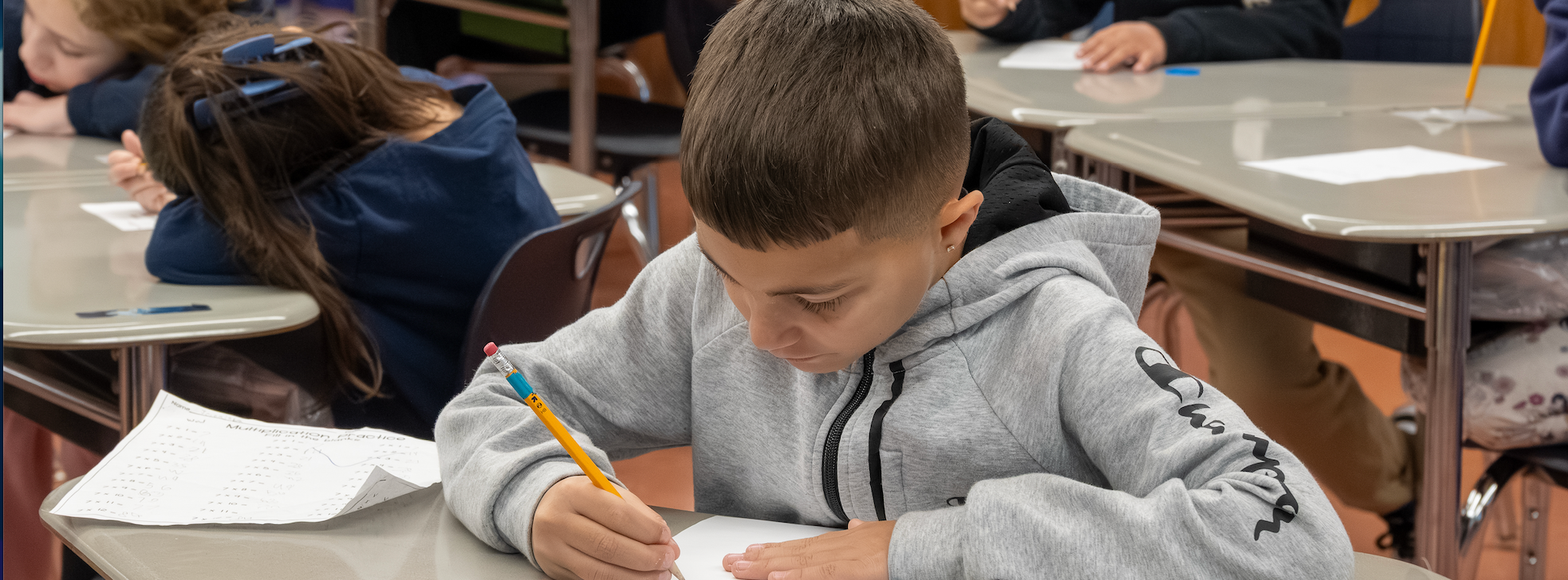 A student works thoughtfully at his desk