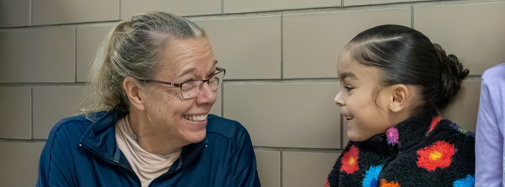 A teacher kneels down to talk to a student