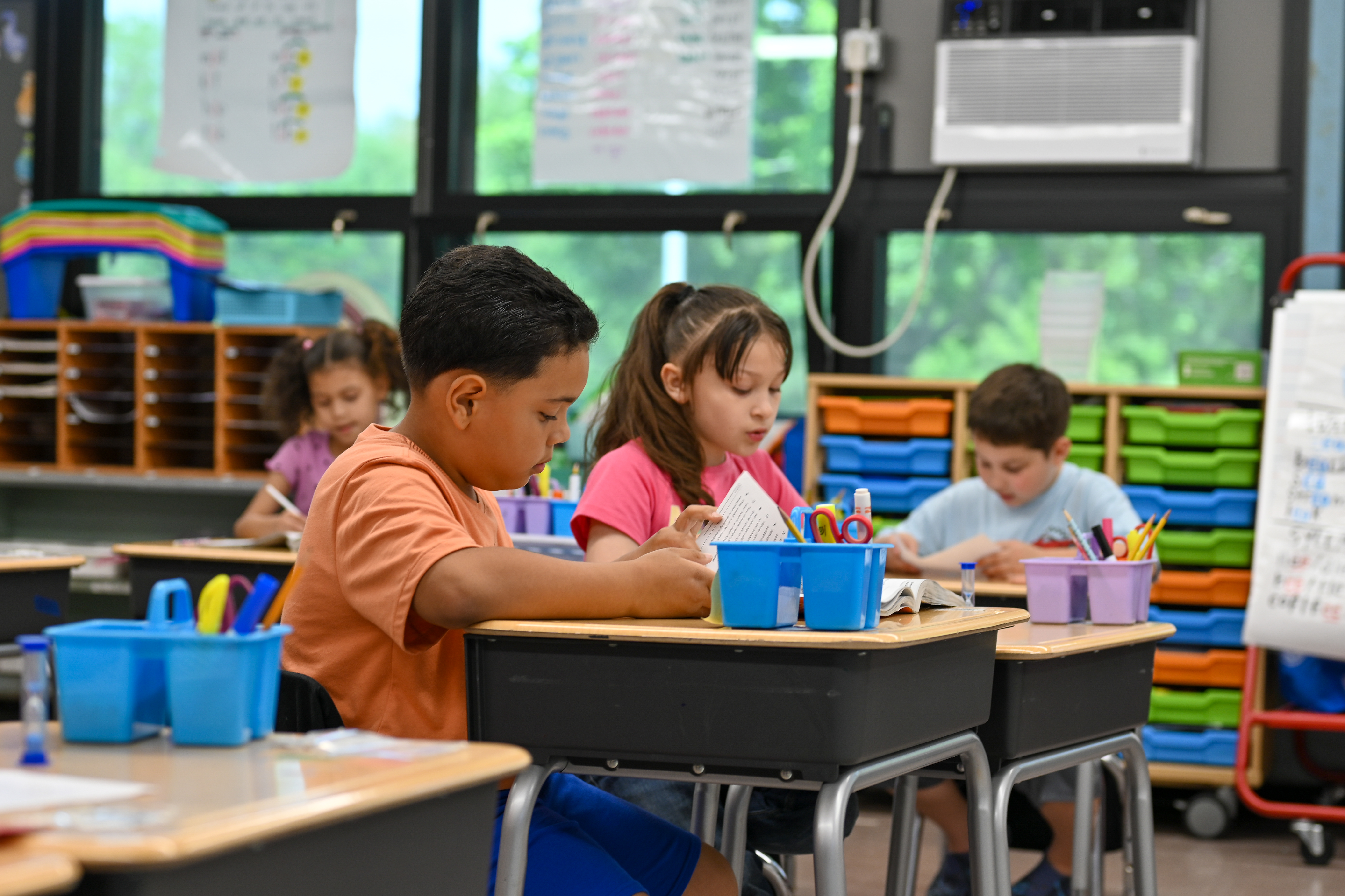 students sitting at a desk writing on an assignment in classroom