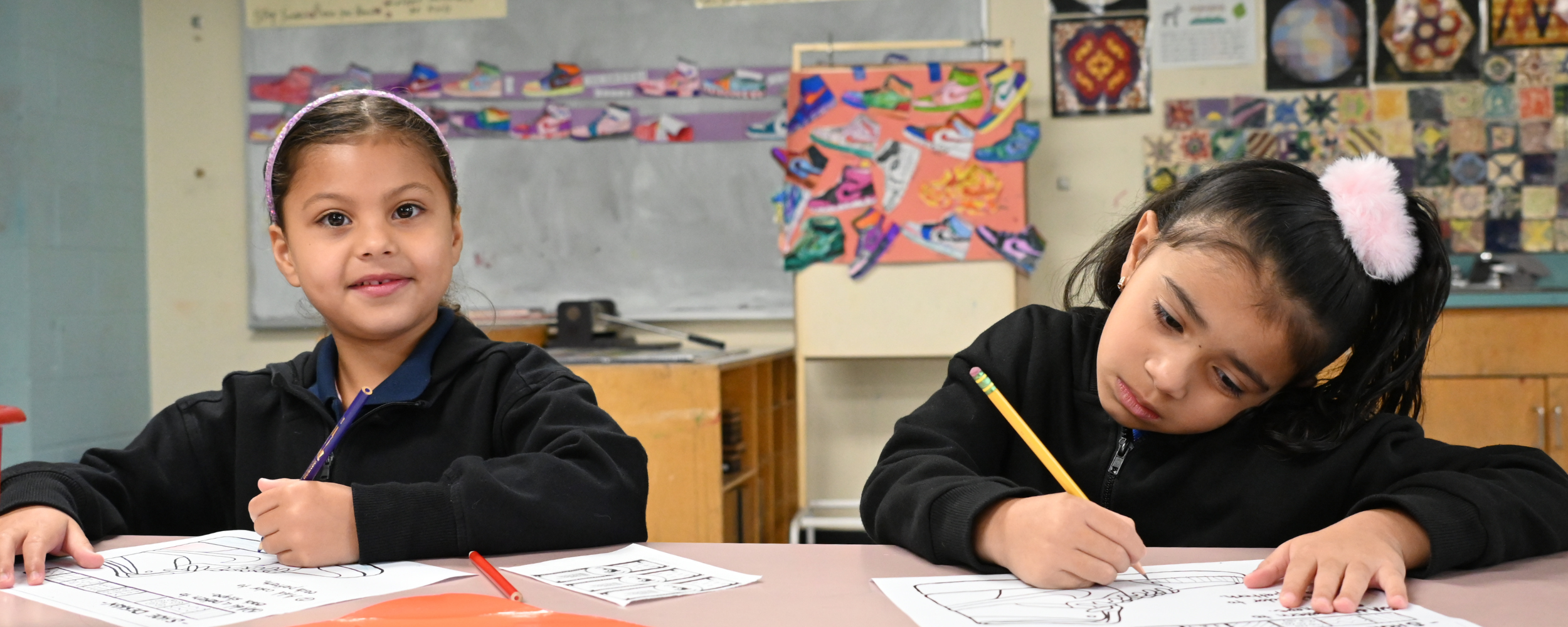 Two students work at a table during art calss