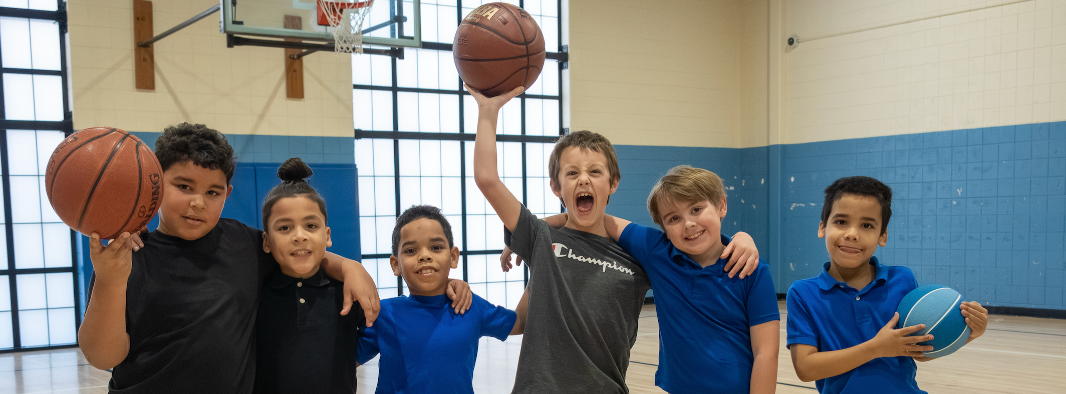 Boys in gym class hold up a basketball