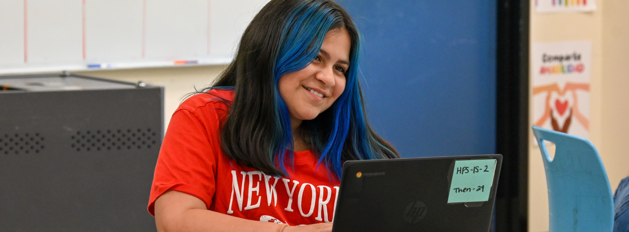student sitting at desk on laptop smiling