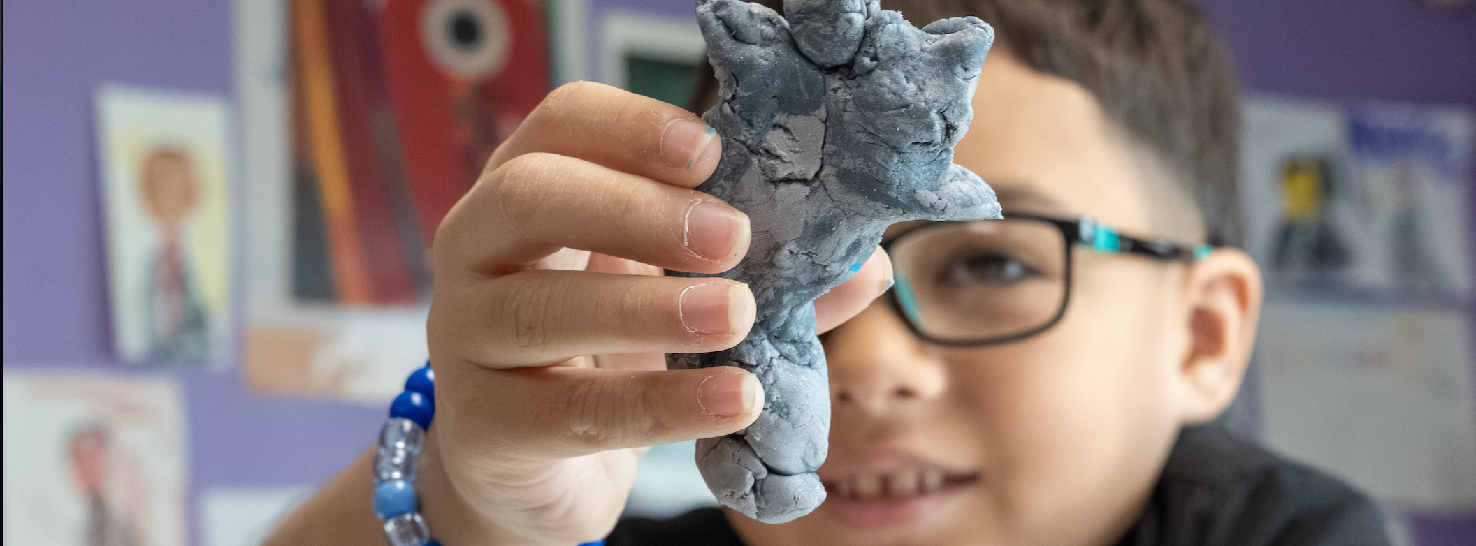 A student holds up his art creation to the camera