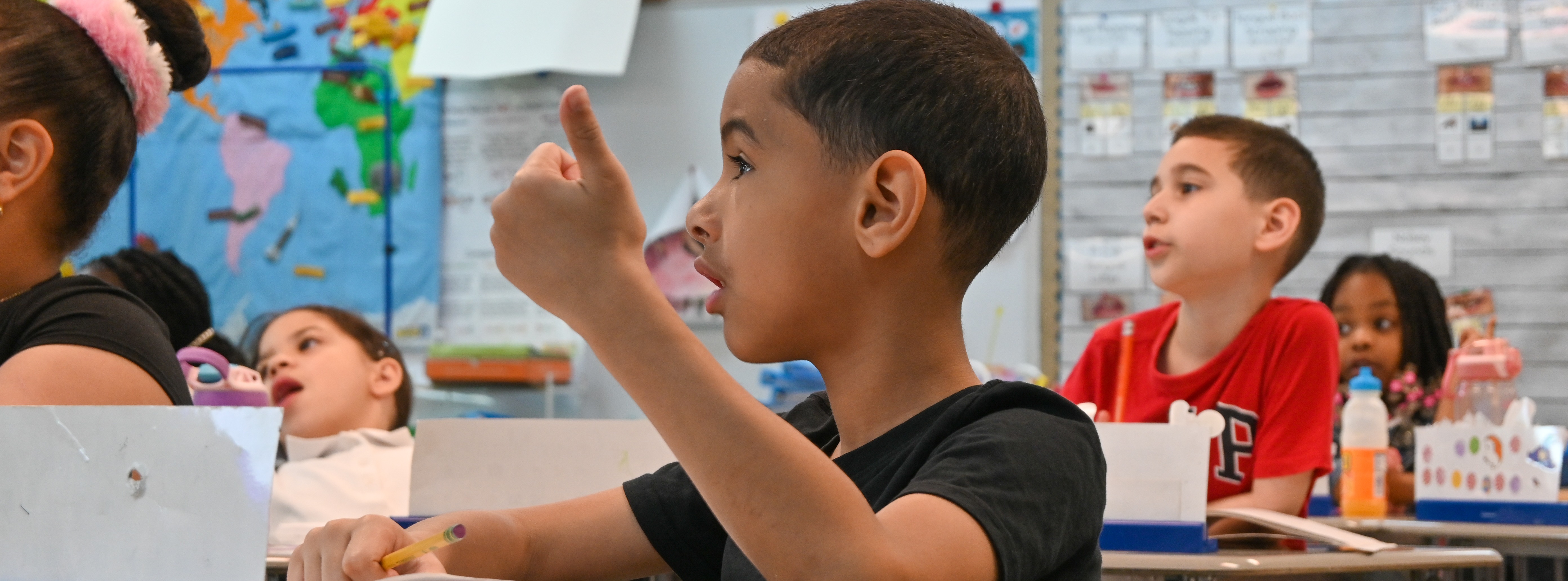 a student participating in class while sitting at his desk