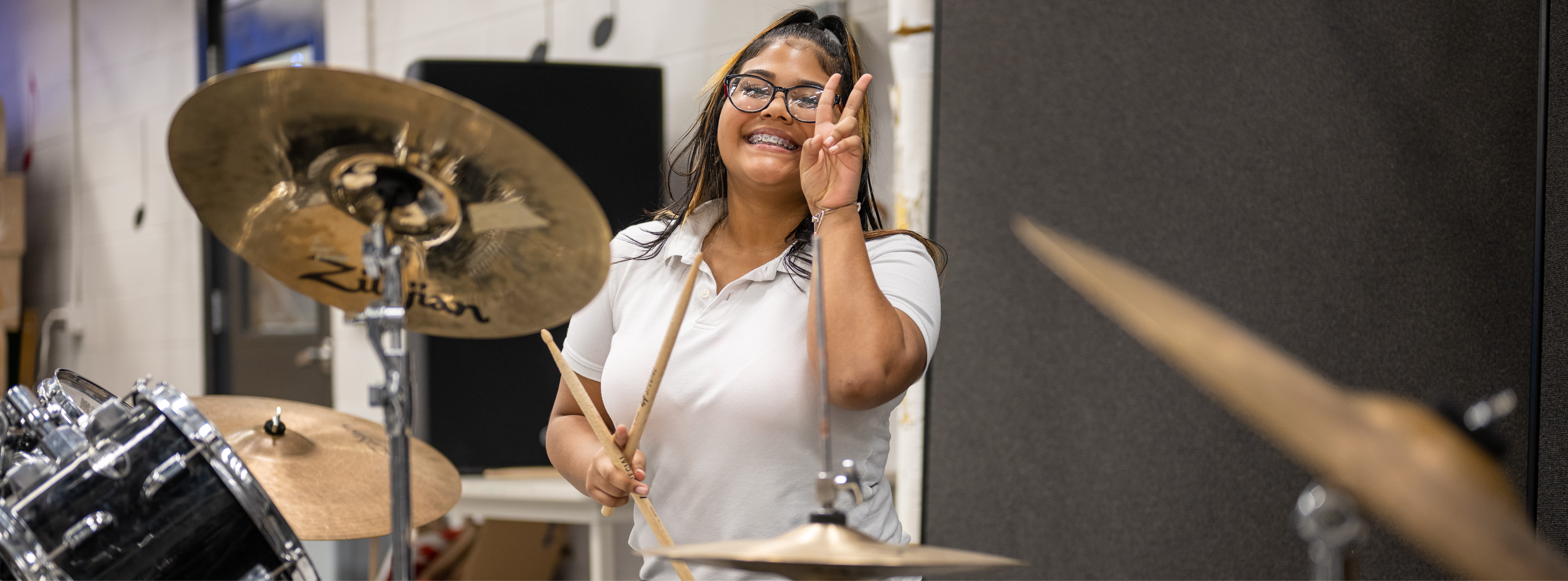 Student with drum sticks in hand smiling for the camera 