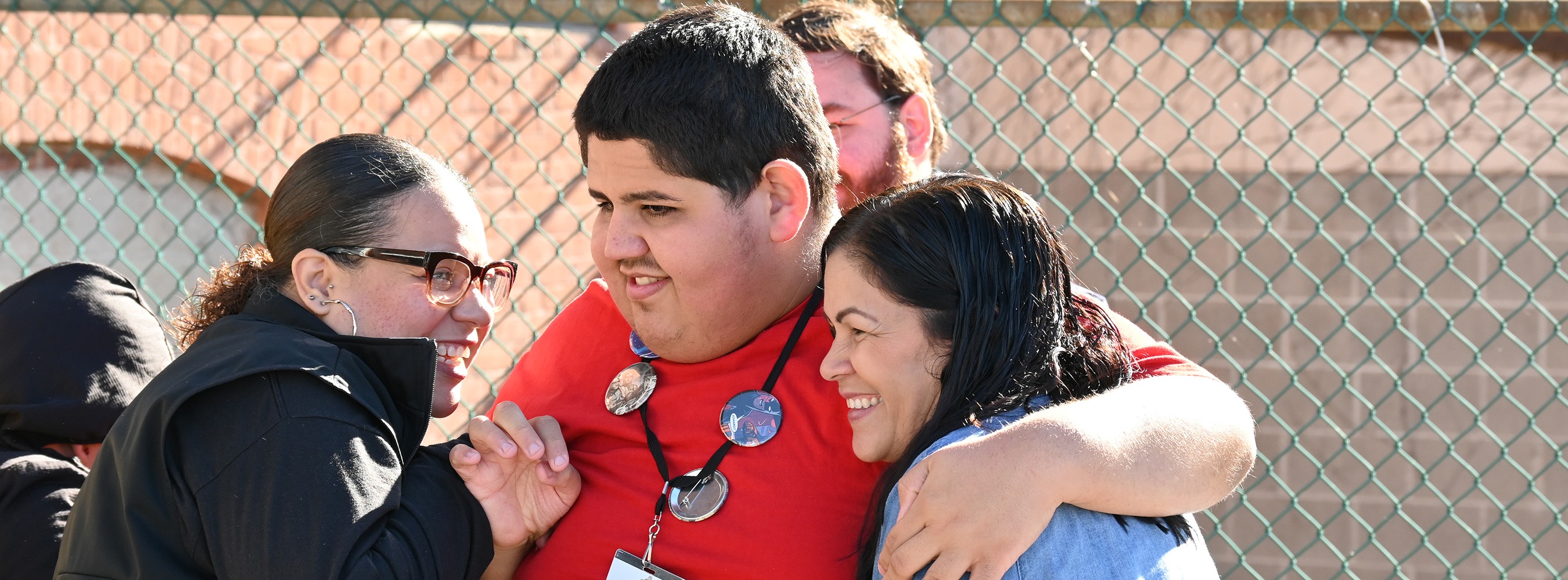 Three staff members embrace a student in the playground