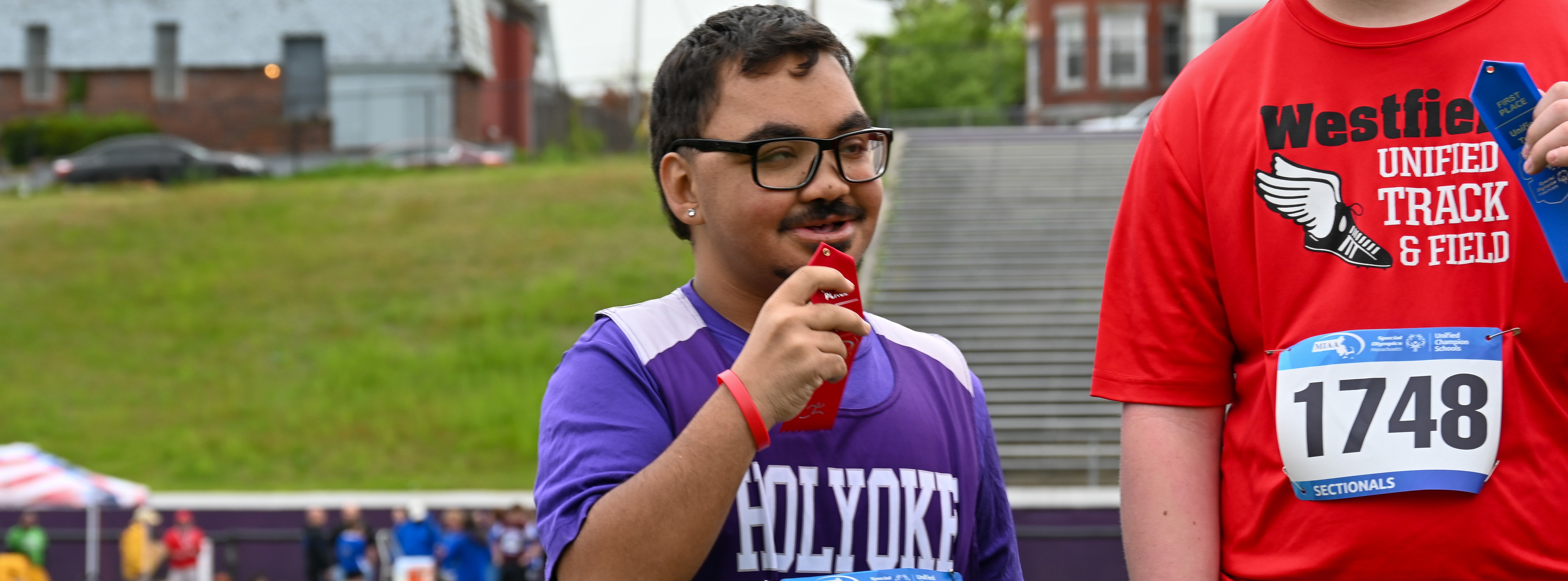 student holds up ribbon from track meet