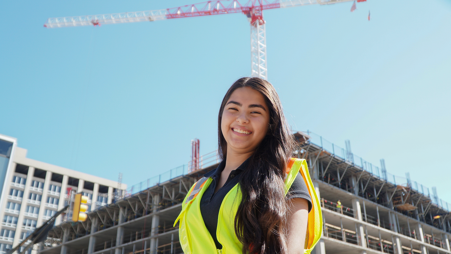 Ana smiling in a neon safety vest on a construction site